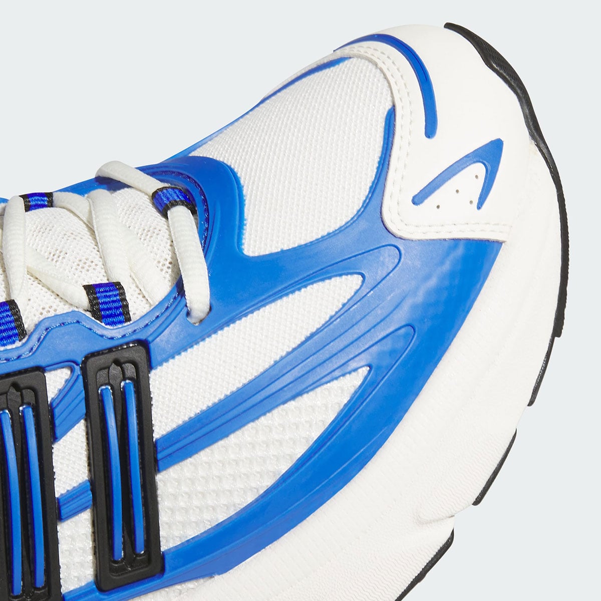 Macro detail of the cobalt TPU cage and black 3-Stripes lockdown across the forefoot of the Adistar XLG 2.0