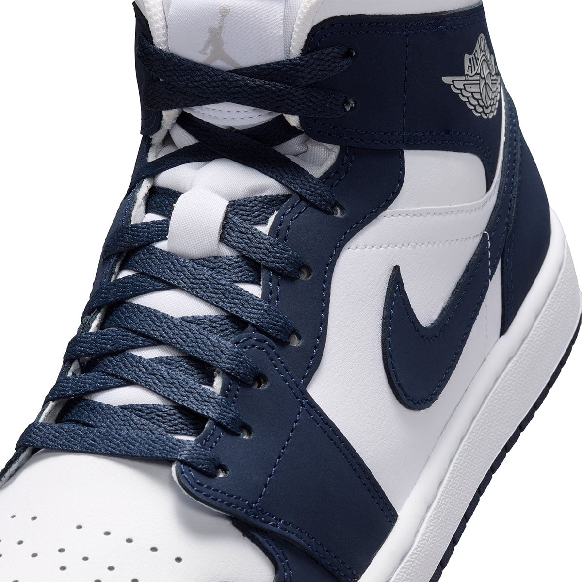 Close-up of the navy Swoosh, toe box perforations and navy laces on the Air Jordan 1 Mid Obsidian