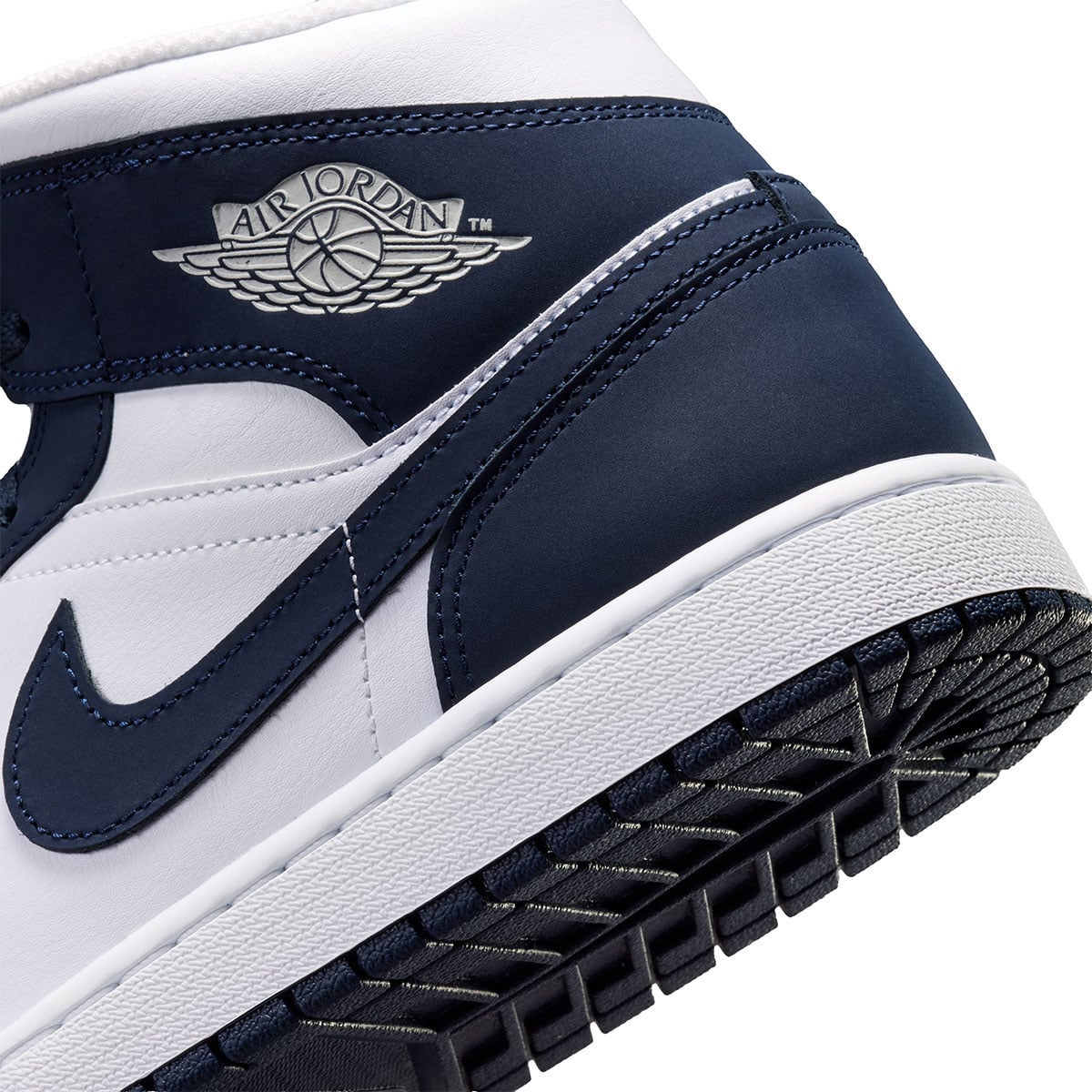 Macro detail of the grey Air Jordan Wings logo on the navy heel of this Jordan 1 Mid colorway