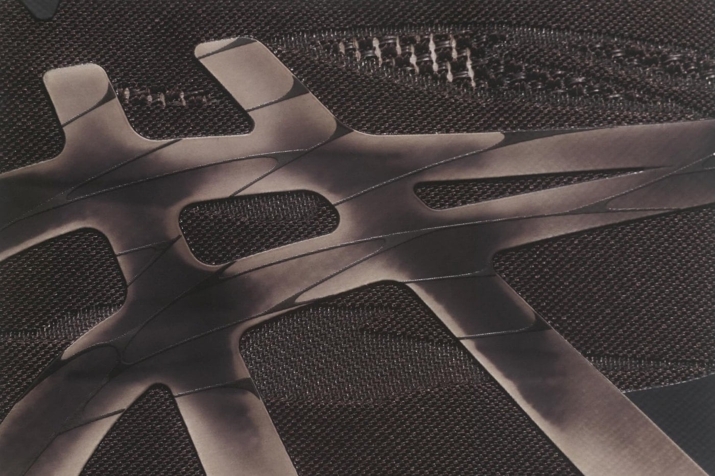 Macro of the sculptural ASICS Stripes overlay laid across the dark mesh upper of the Superblast 3 BT