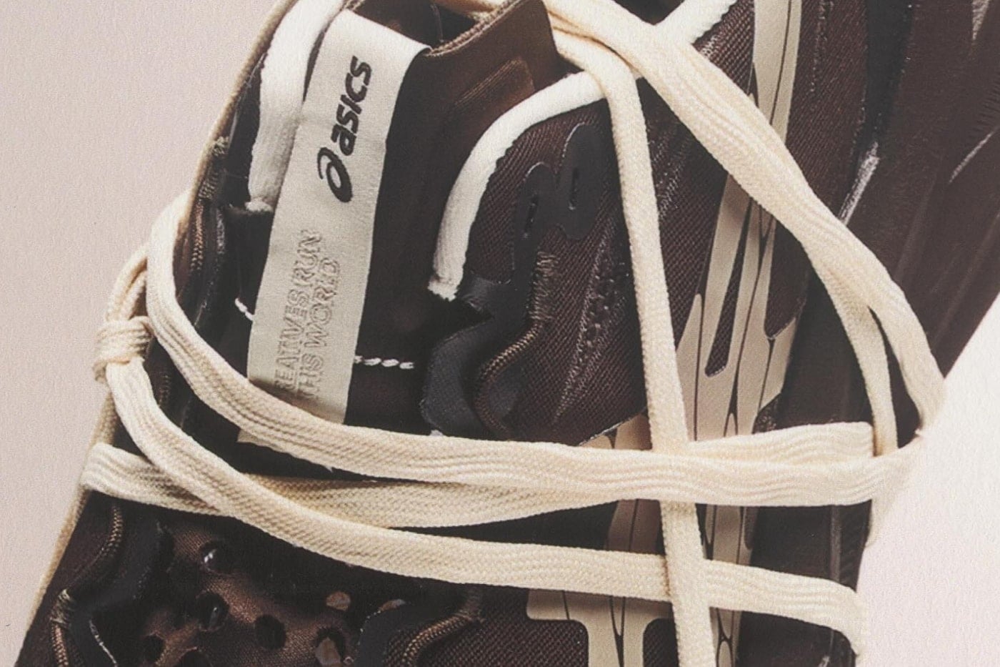 Tongue detail with the asics logo and a woven "Creatives Run This World" tag wrapped in cream laces on the brown upper