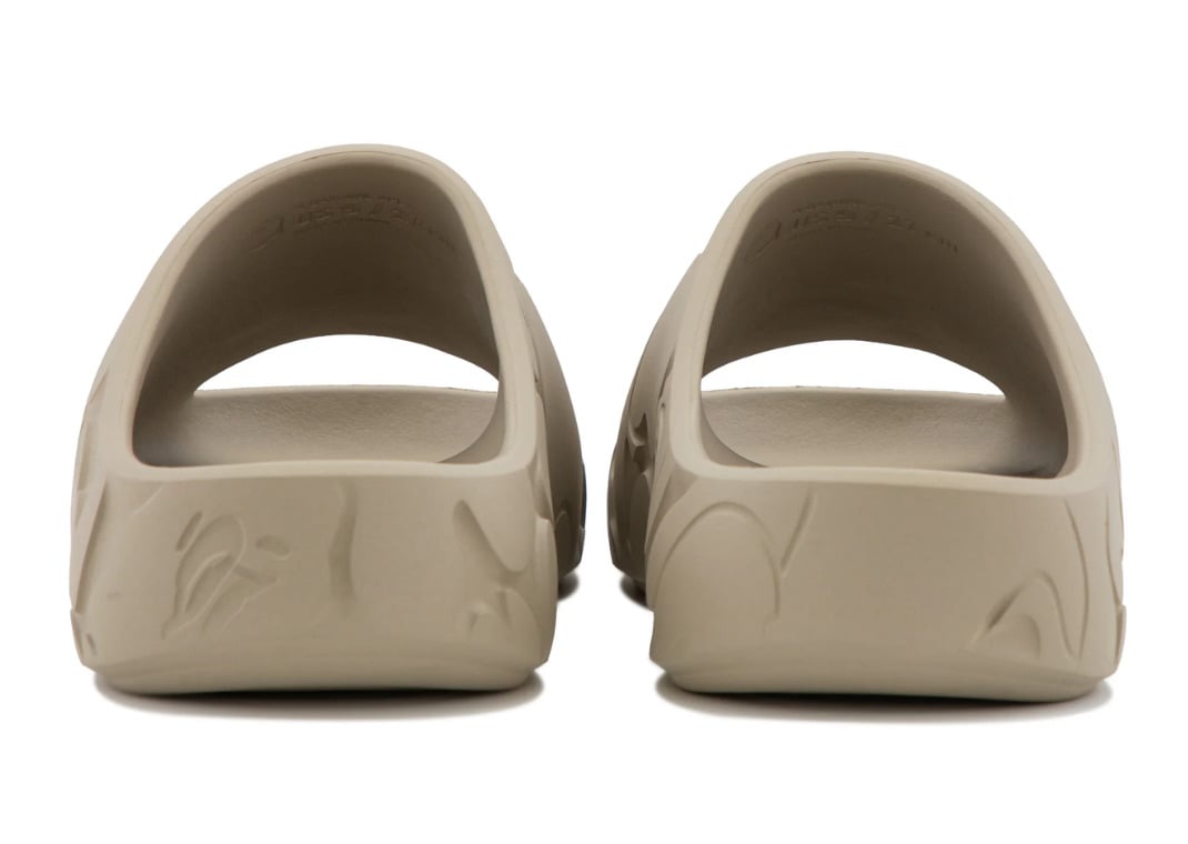 Heel view of the beige pair, the camo molding wrapping the back of each slip-on slide