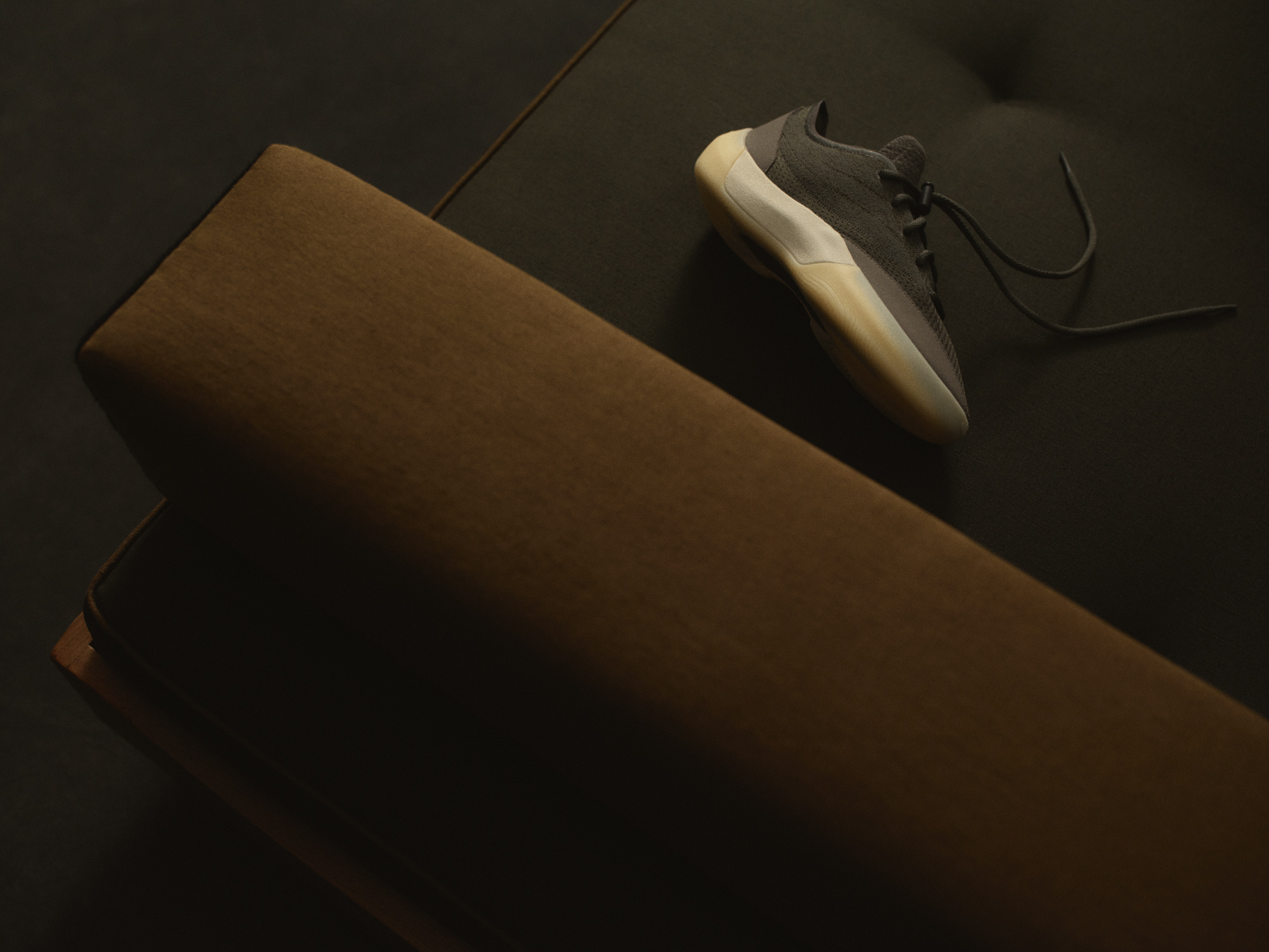 Fear of God Athletics III Basketball "Cinder" placed on a dark architectural surface in editorial styling