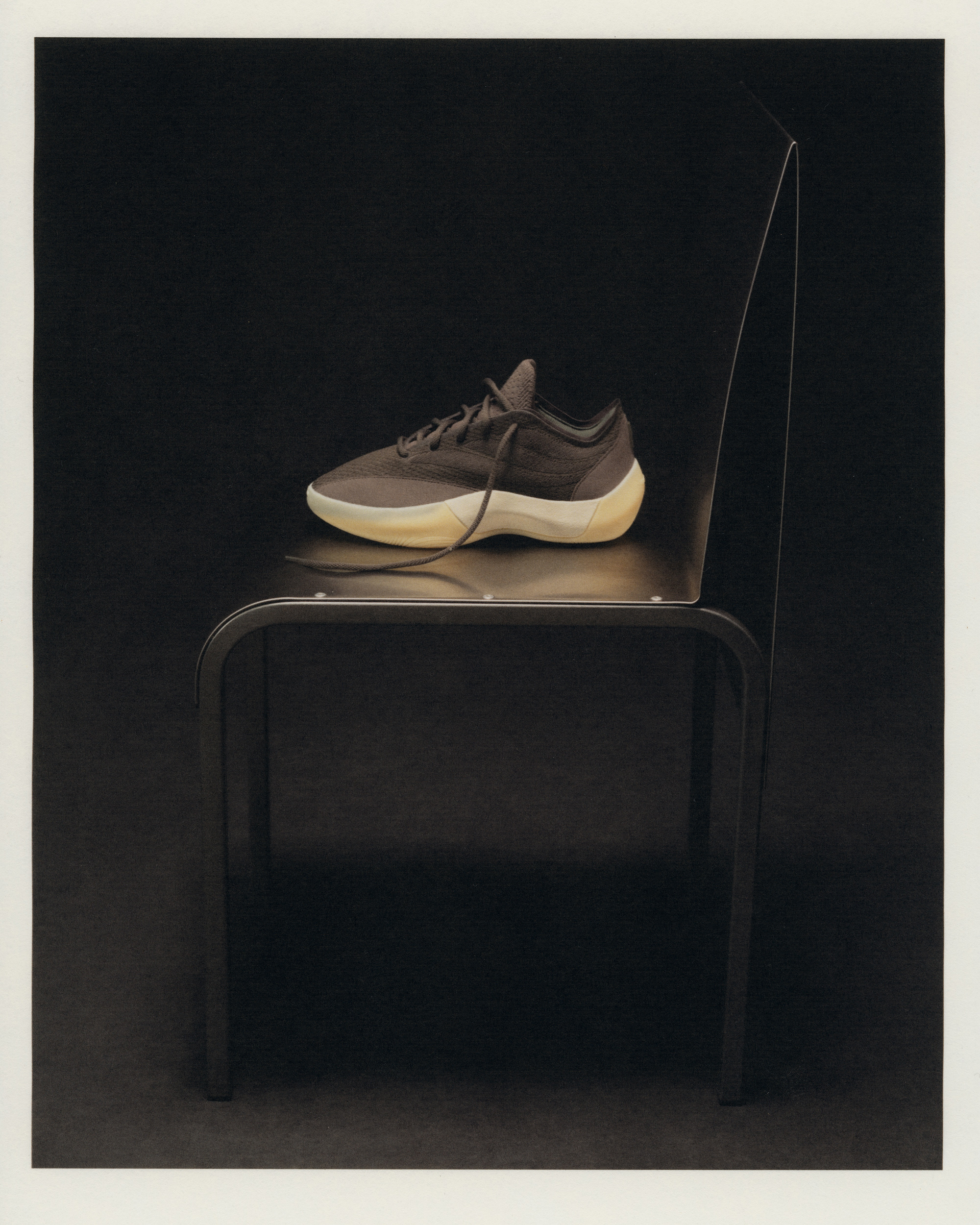 Fear of God Athletics III Basketball "Cinder" displayed on a black metal-framed chair in editorial styling