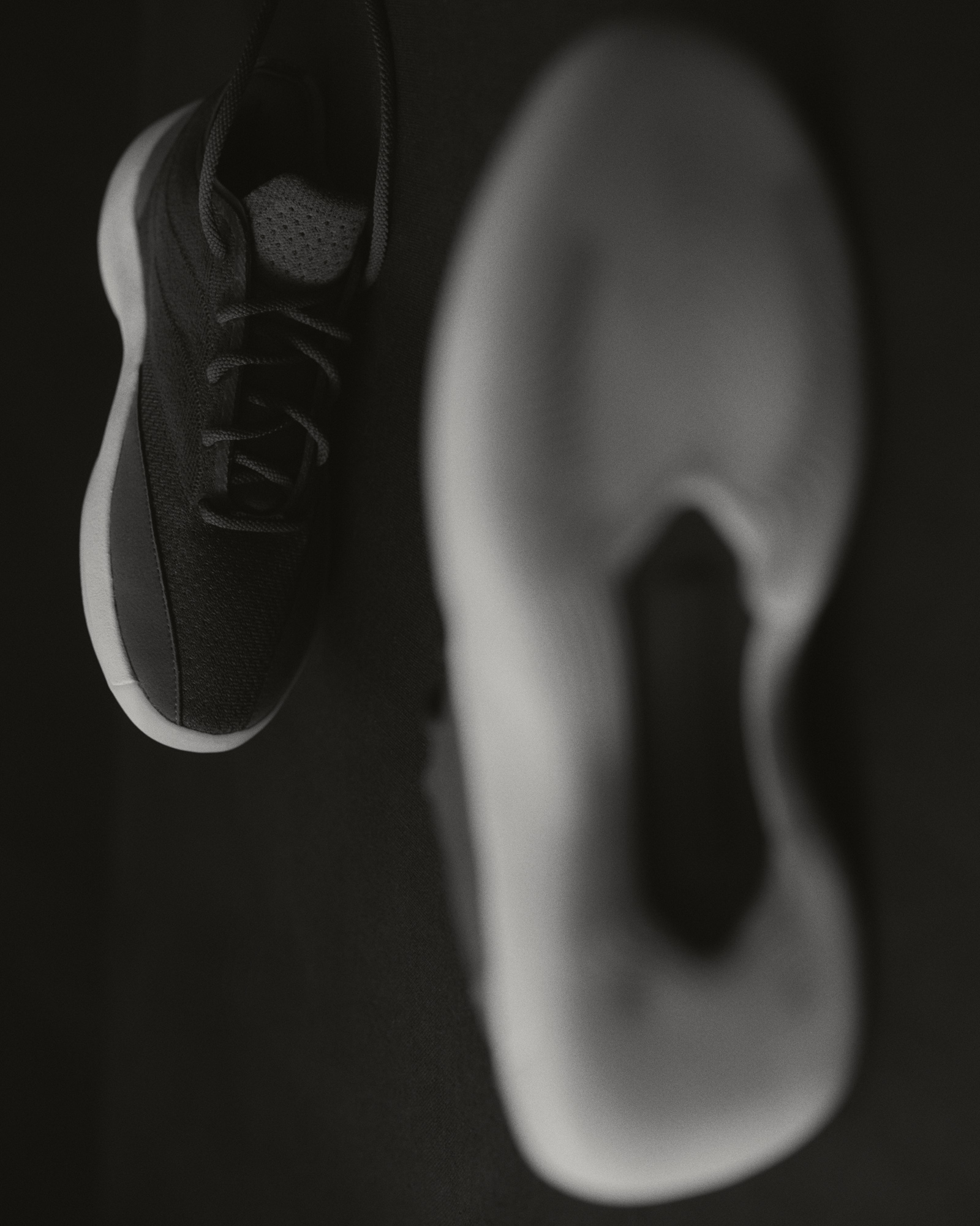 Black-and-white editorial of the Fear of God Athletics III Basketball "Cinder" pair with abstract reflection