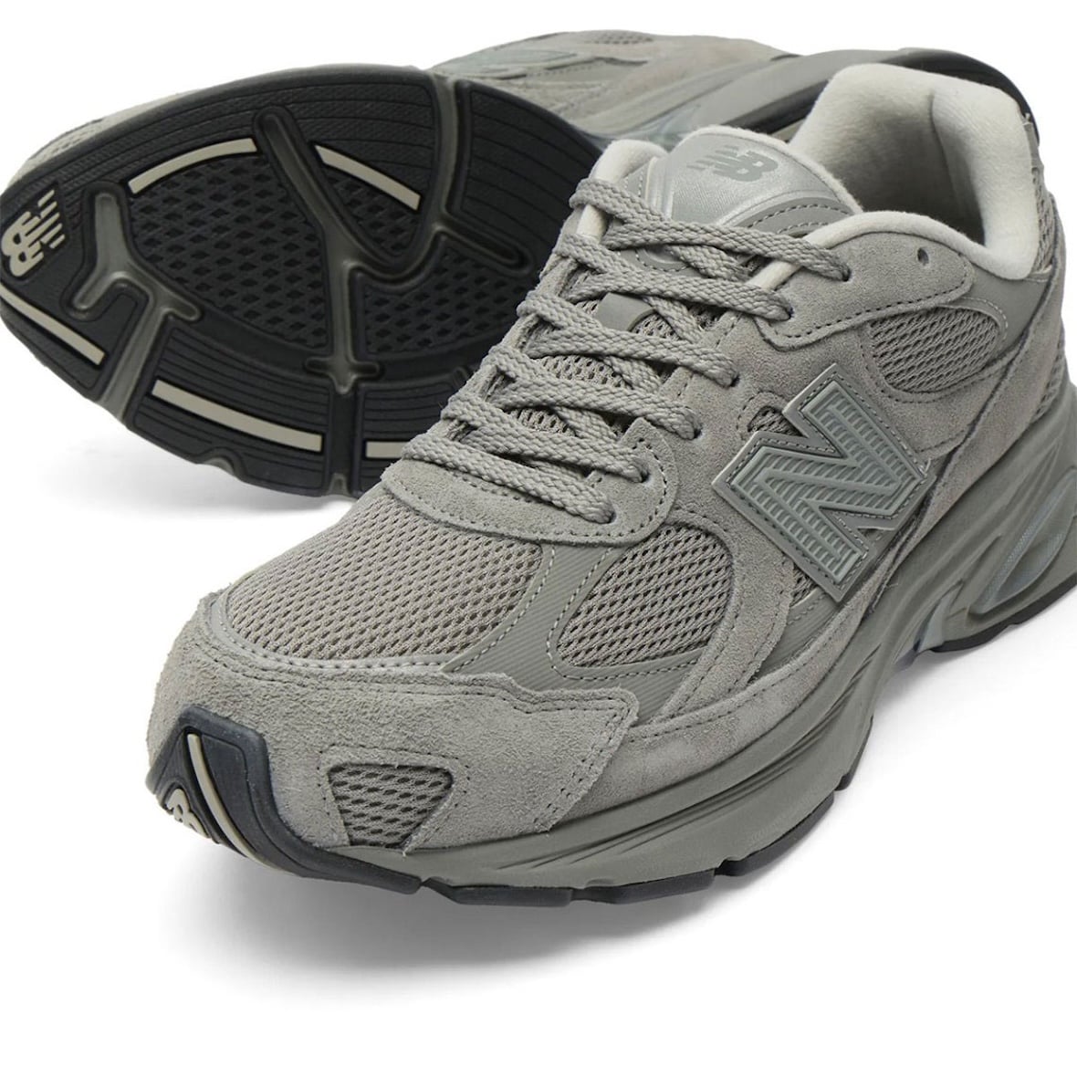 Front view paired with a flipped shoe showing the black ABZORB outsole tread of the New Balance 2010 Harbor Grey