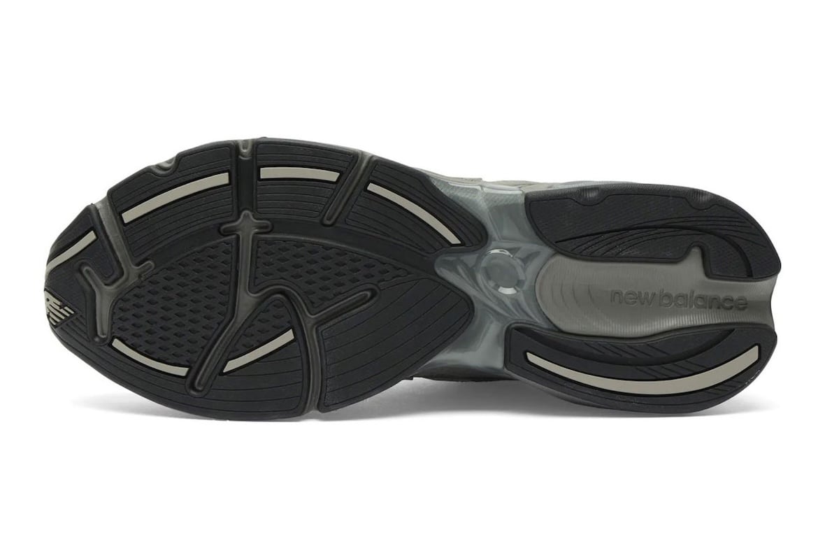 Bottom outsole view of the New Balance 2010 with black tread, taupe grip accents, and molded new balance script