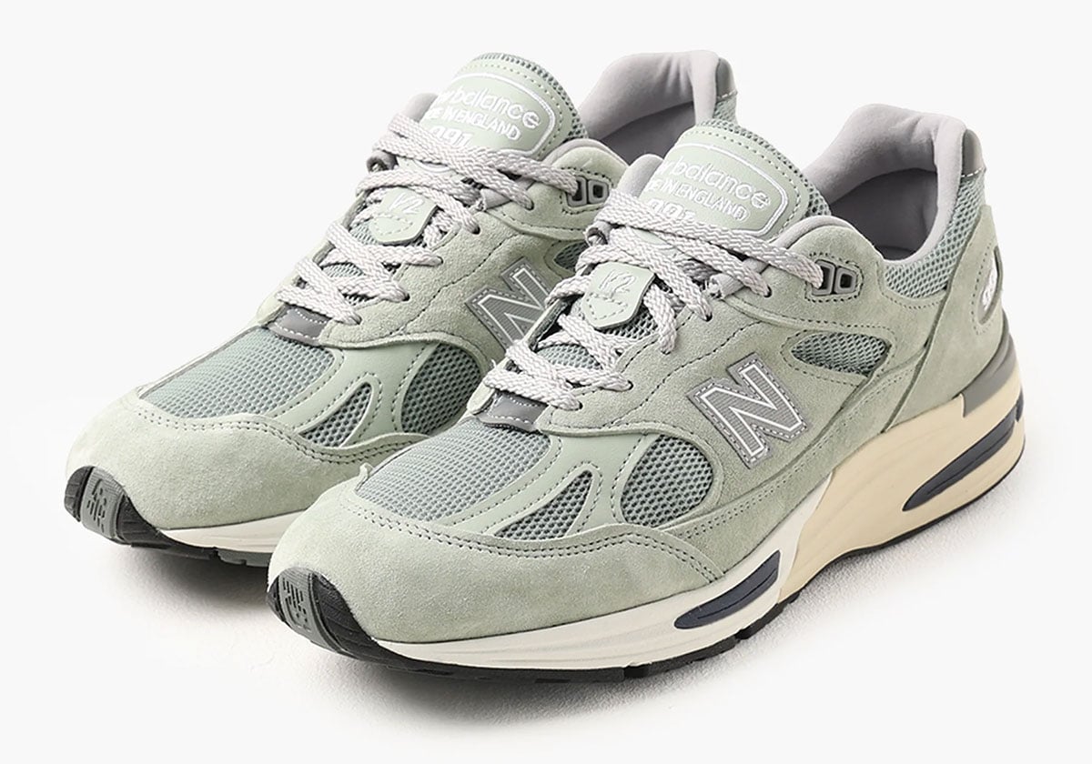 Front three-quarter view of the pair, tongues stamped "new balance MADE in ENGLAND" over grey collars
