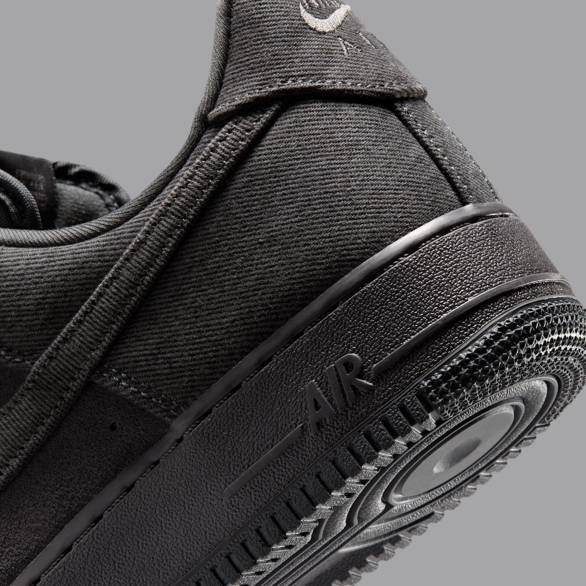Macro detail of the black midsole with debossed AIR text beneath the washed denim quarter panel