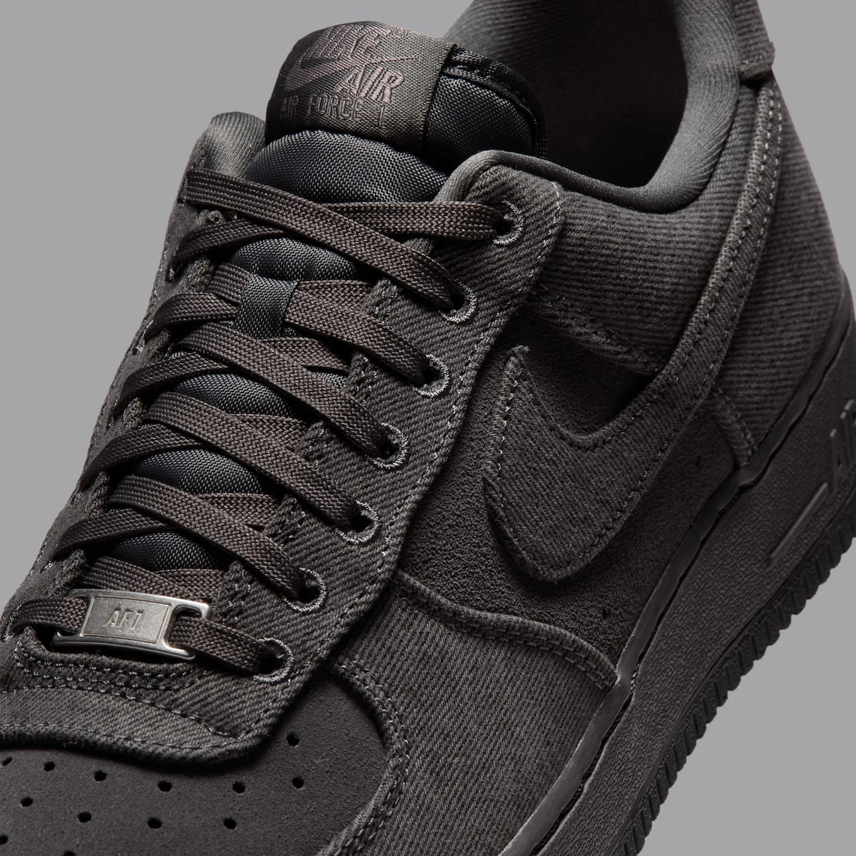 Close-up of the suede Swoosh and polished silver AF1 lace dubrae on the Anthracite denim Air Force 1 Low
