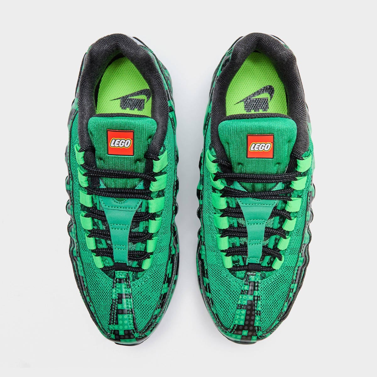 Top-down look at the green LEGO Air Max 95, showing red LEGO logo tongue tabs and a debossed black Nike Swoosh on the insoles