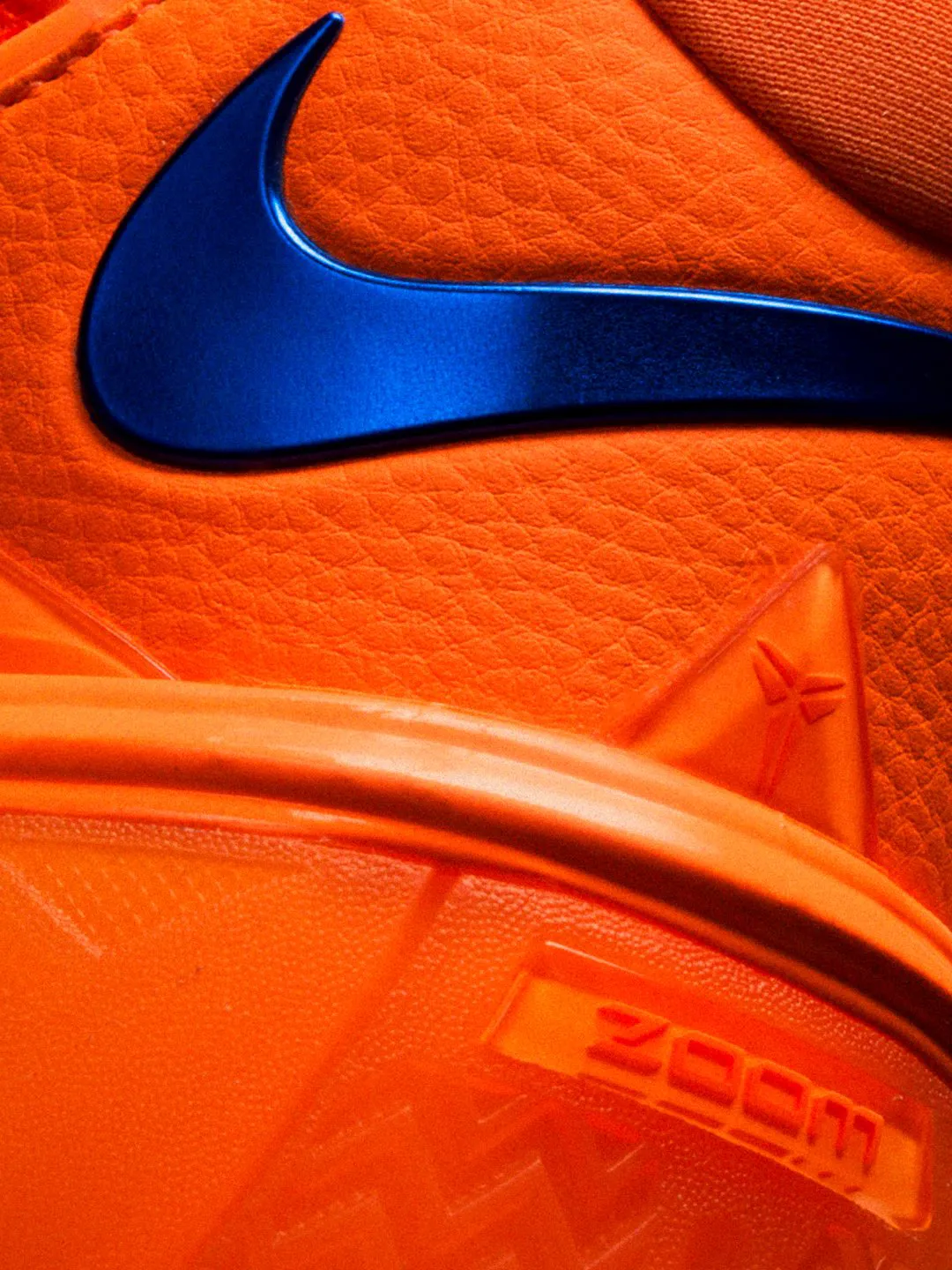 Macro detail of the metallic blue Swoosh, embossed Kobe sheath logo and Zoom branding on the orange Kobe 3 Low Knicks PE