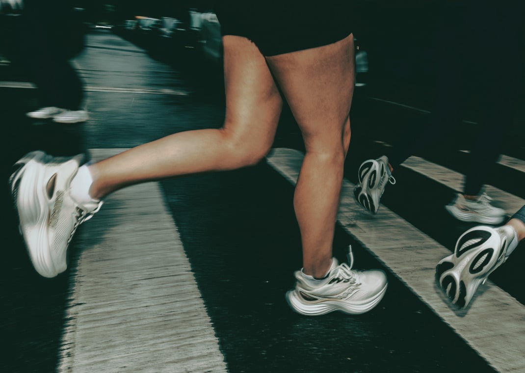 Runner mid-stride on a crosswalk in the cream Saucony Triumph 24 during a city training run