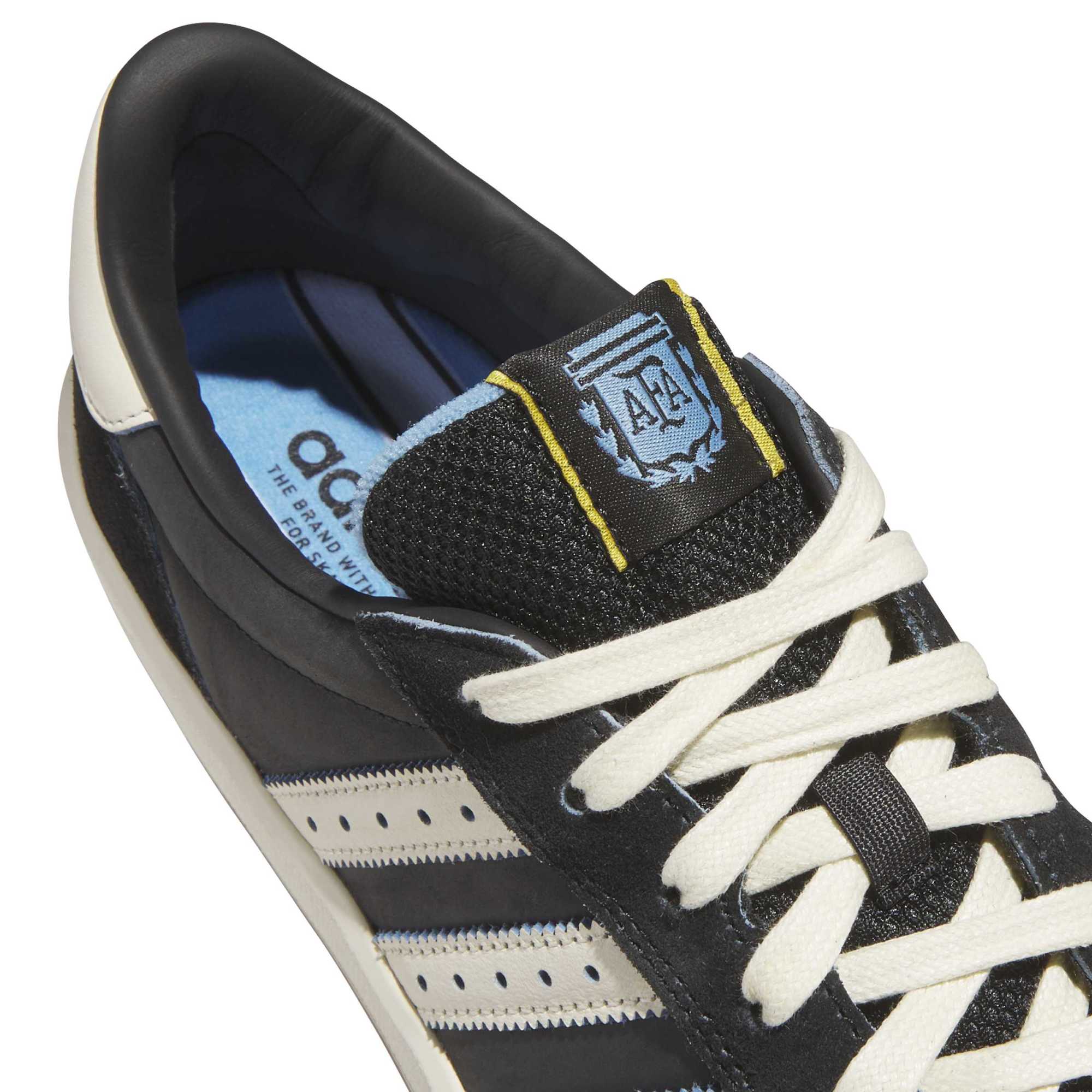 Close-up of the sky-blue AFA Argentina crest tongue tag with yellow trim and cream laces on the Glenburn