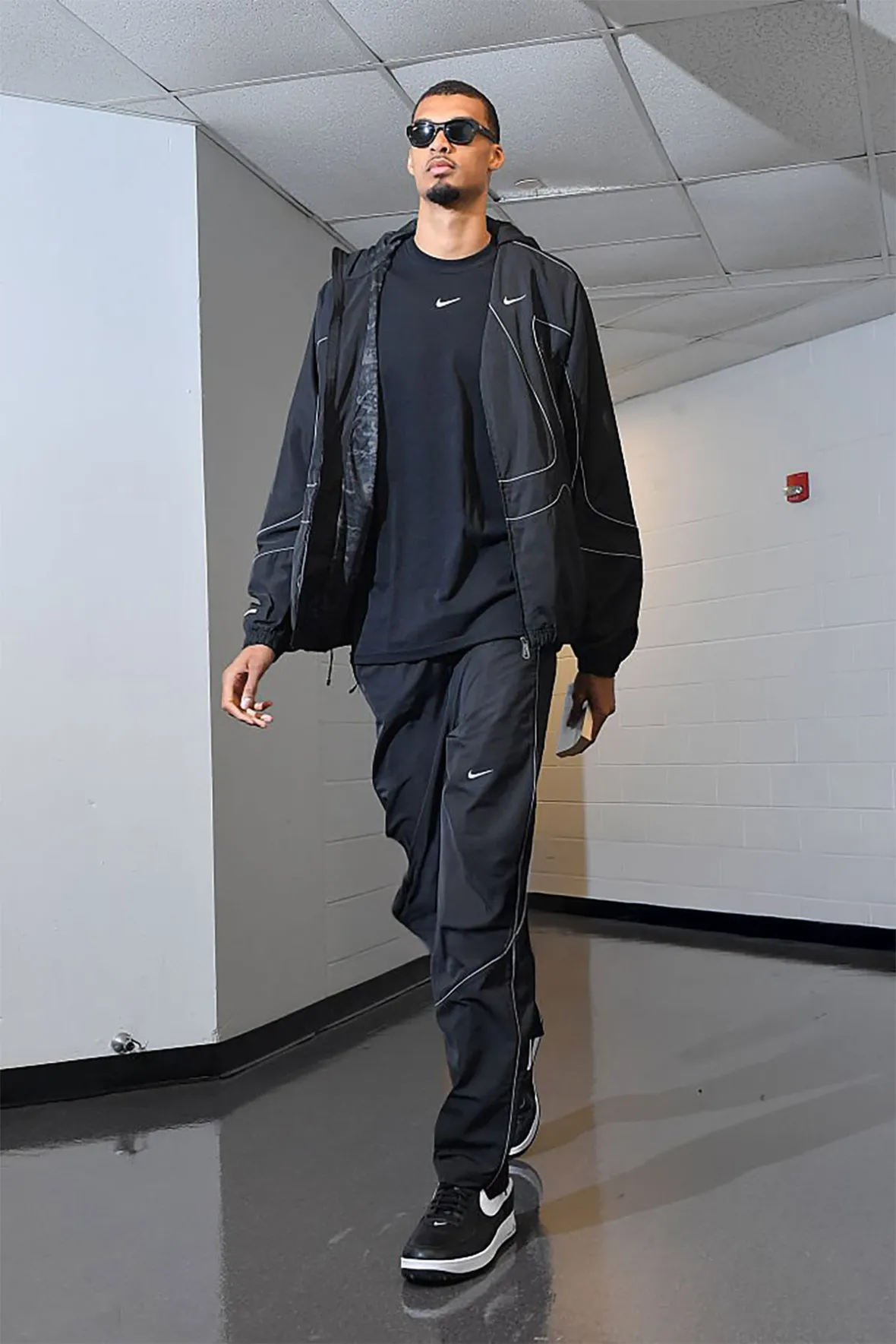 Victor Wembanyama walking the Western Conference Finals tunnel in a black Nike tracksuit and the Victor Victor Air Force 1 Low