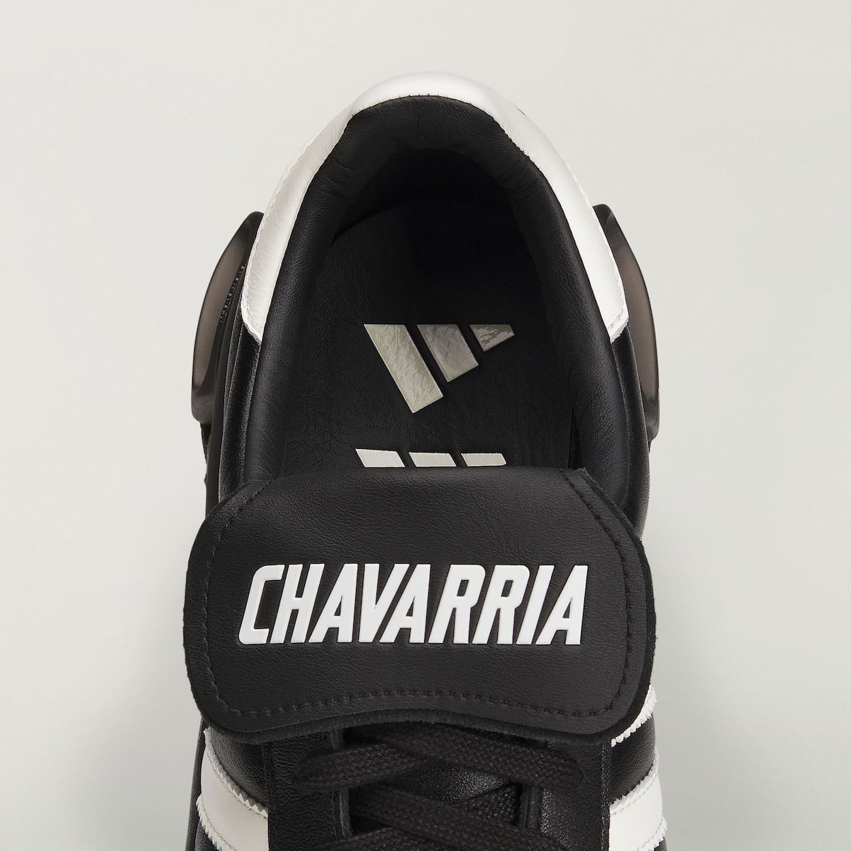 Macro of the fold-over tongue with white CHAVARRIA lettering and adidas logo on the black leather sockliner