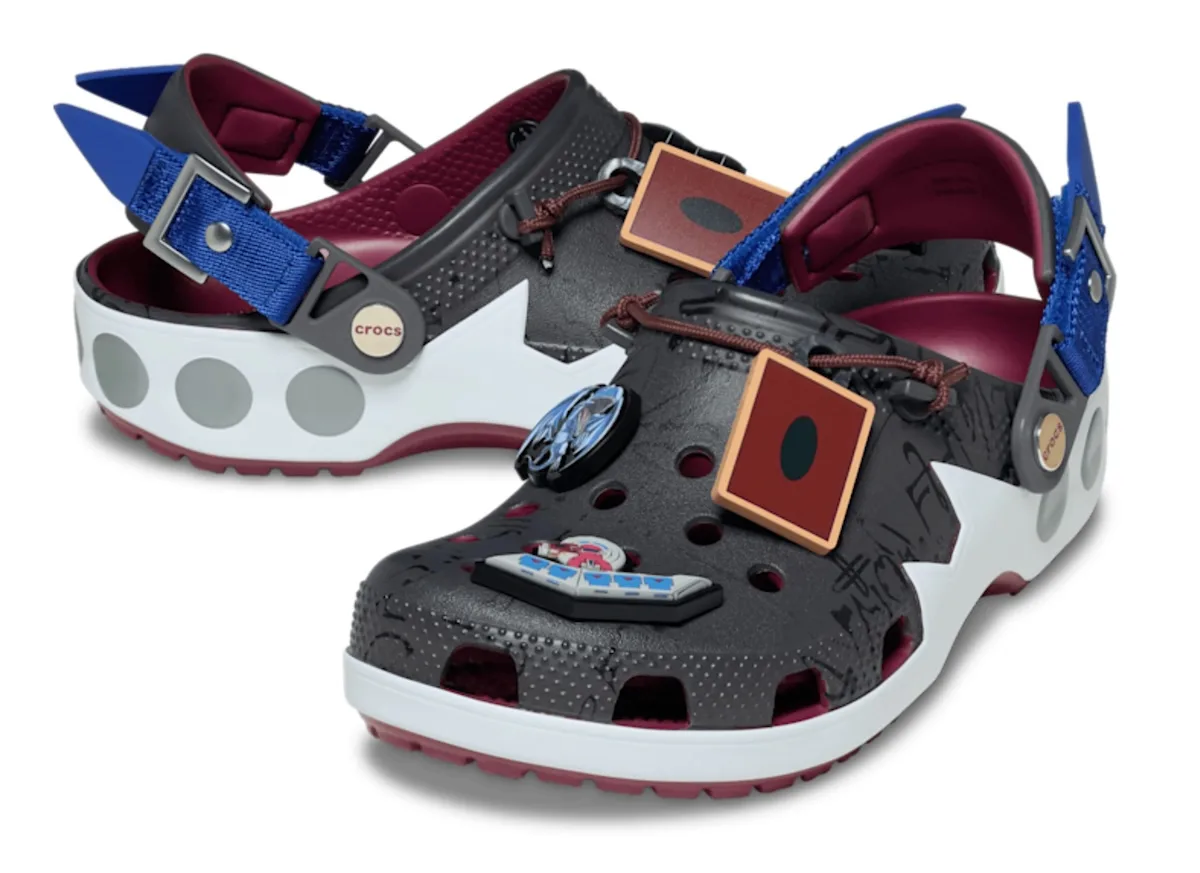 angled pair, black clogs with white sole, blue buckle straps and rust card charms, x Crocs Collection