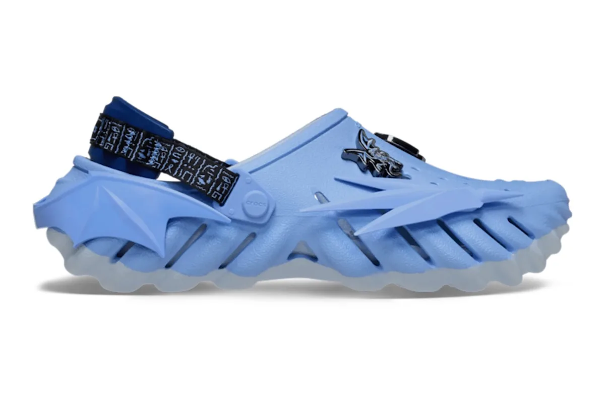 lateral view, pale blue spiky clog with dragon charm and hieroglyph-print strap, x Crocs Collection