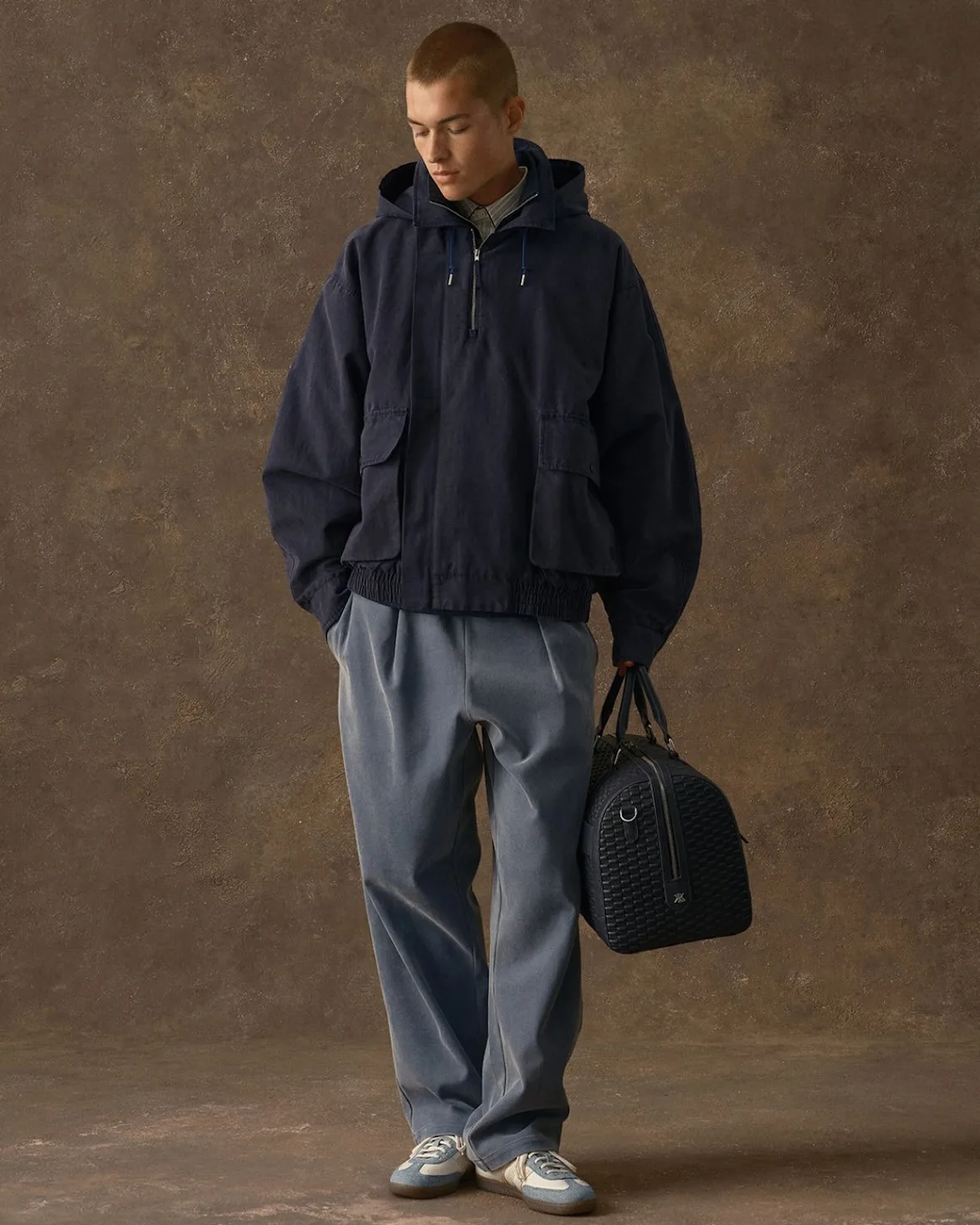 on-foot with navy hooded jacket, grey trousers and black duffel bag, Denim