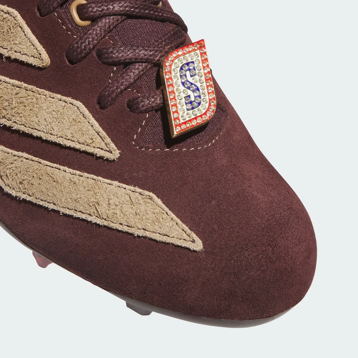 toe close-up, diamond-studded gold S charm beside tan suede stripes, II x Snickers