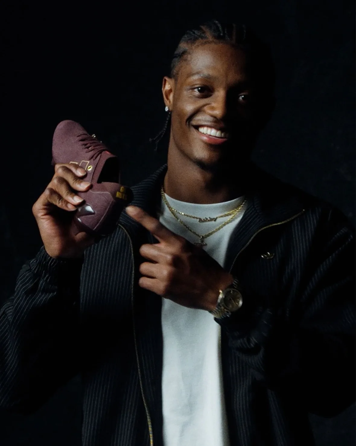 in-hand shot, man pointing at maroon suede shoe against black backdrop, II x Snickers