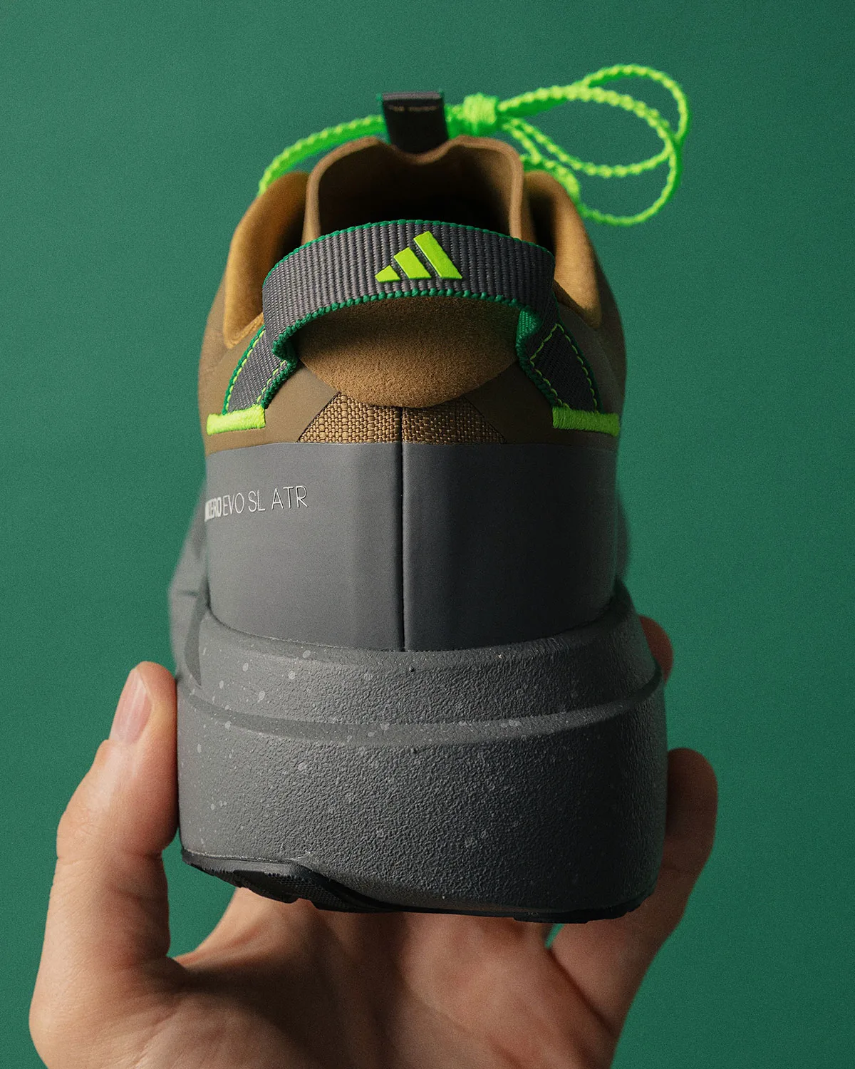 heel view in hand, adidas logo tab, green laces looped, speckled gray midsole, x Up There