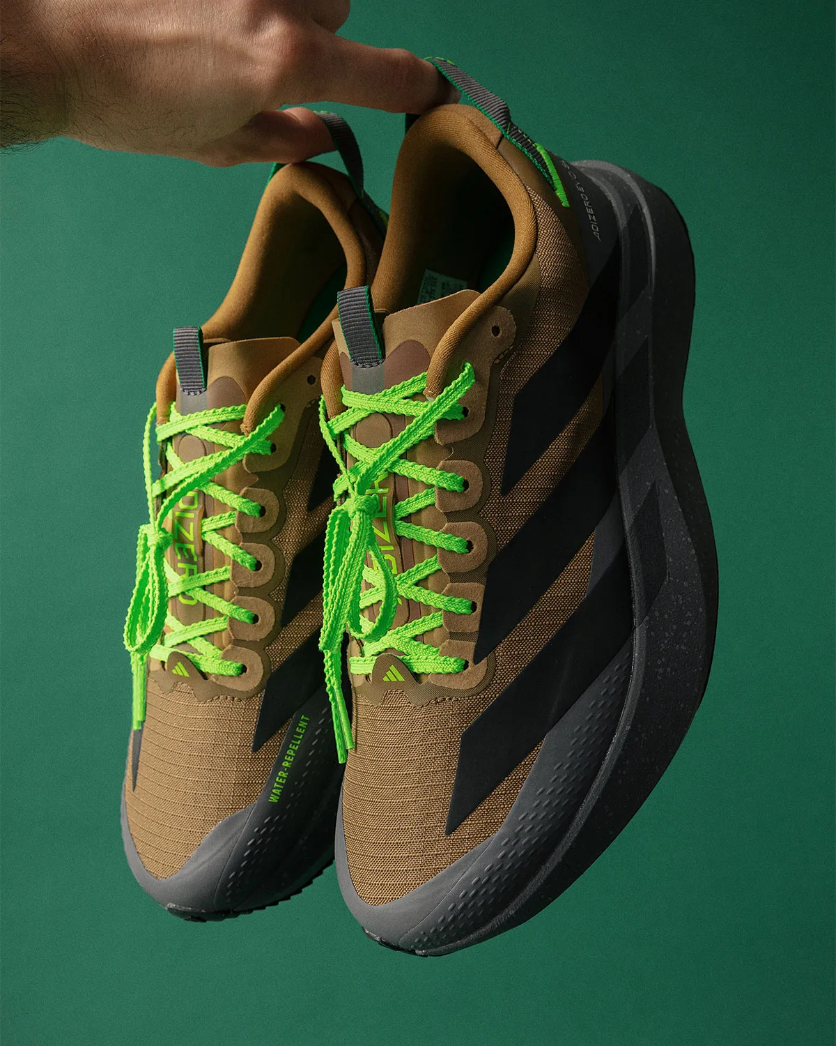 pair held by heel loops, brown-black upper, neon green laces, black midsole, x Up There