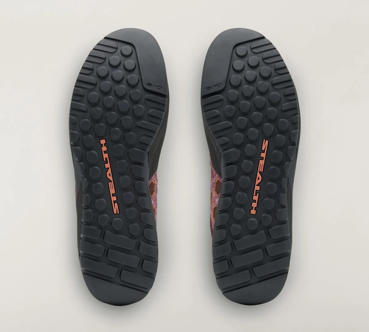 outsole view of mauve approach shoe pair with orange Stealth branding and lug tread, Approach and Niad
