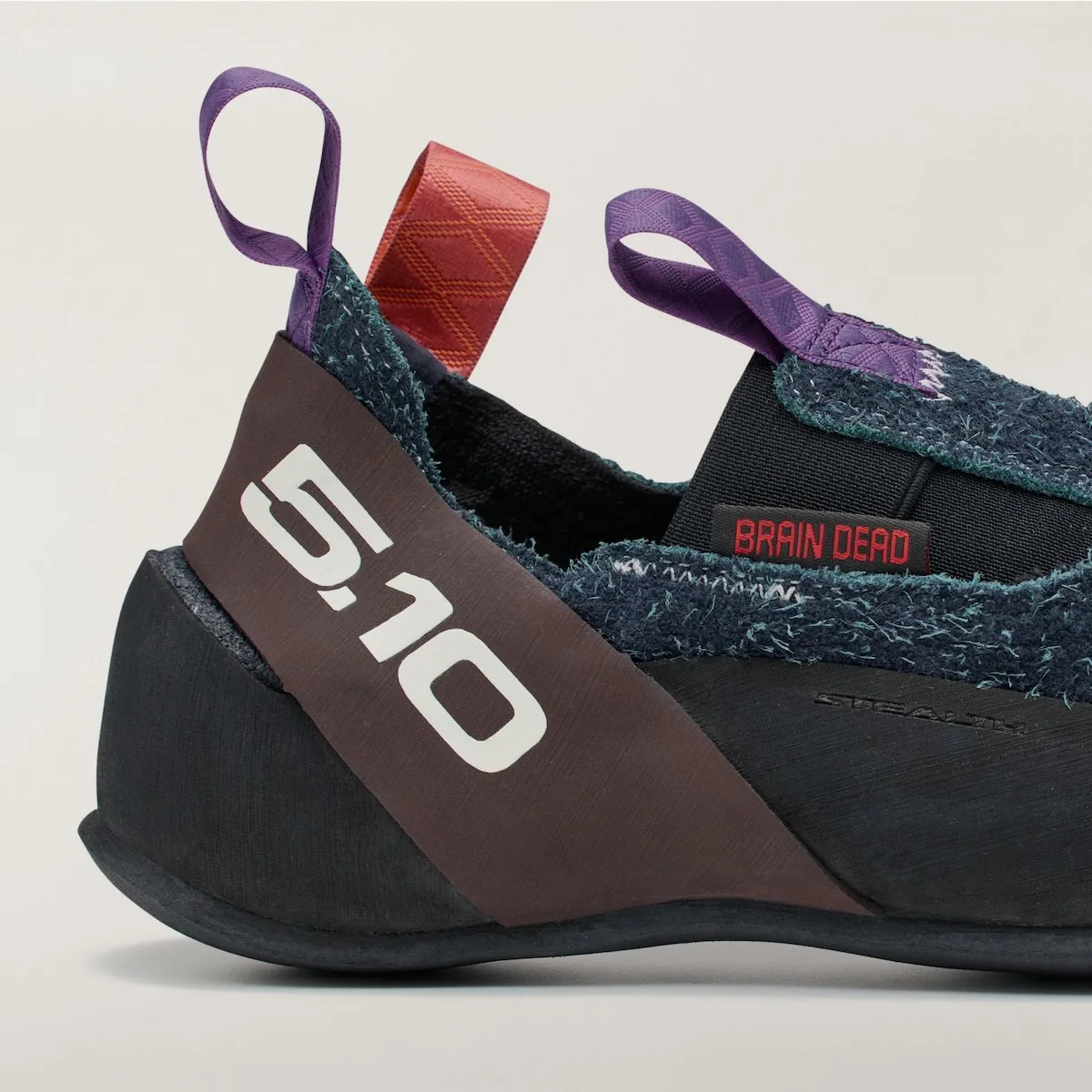 heel detail of navy slip-on shoe with purple and red pull loops and Brain Dead patch, Approach and Niad