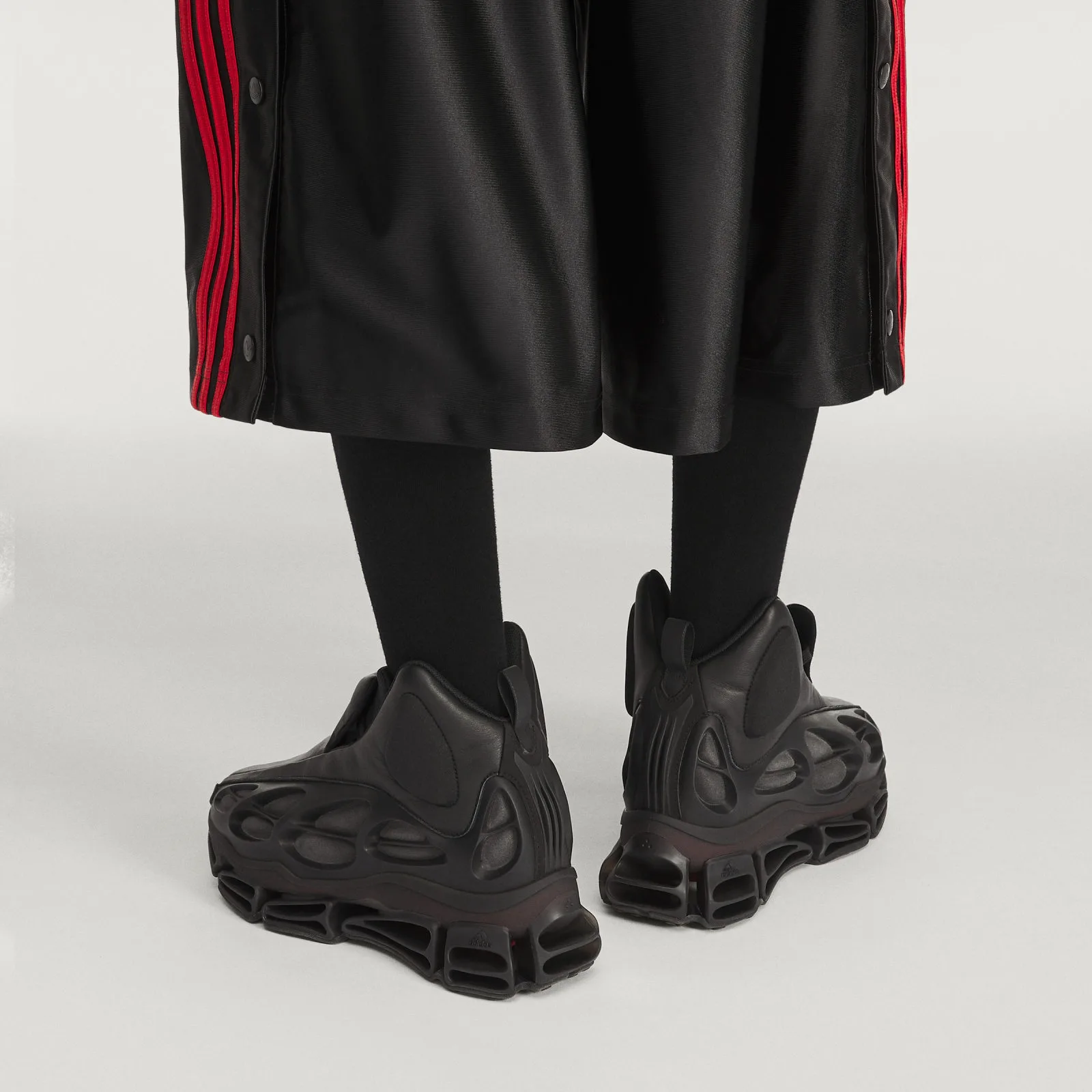 on-foot heel view, black trousers with red side stripes, black hosiery, Wolf