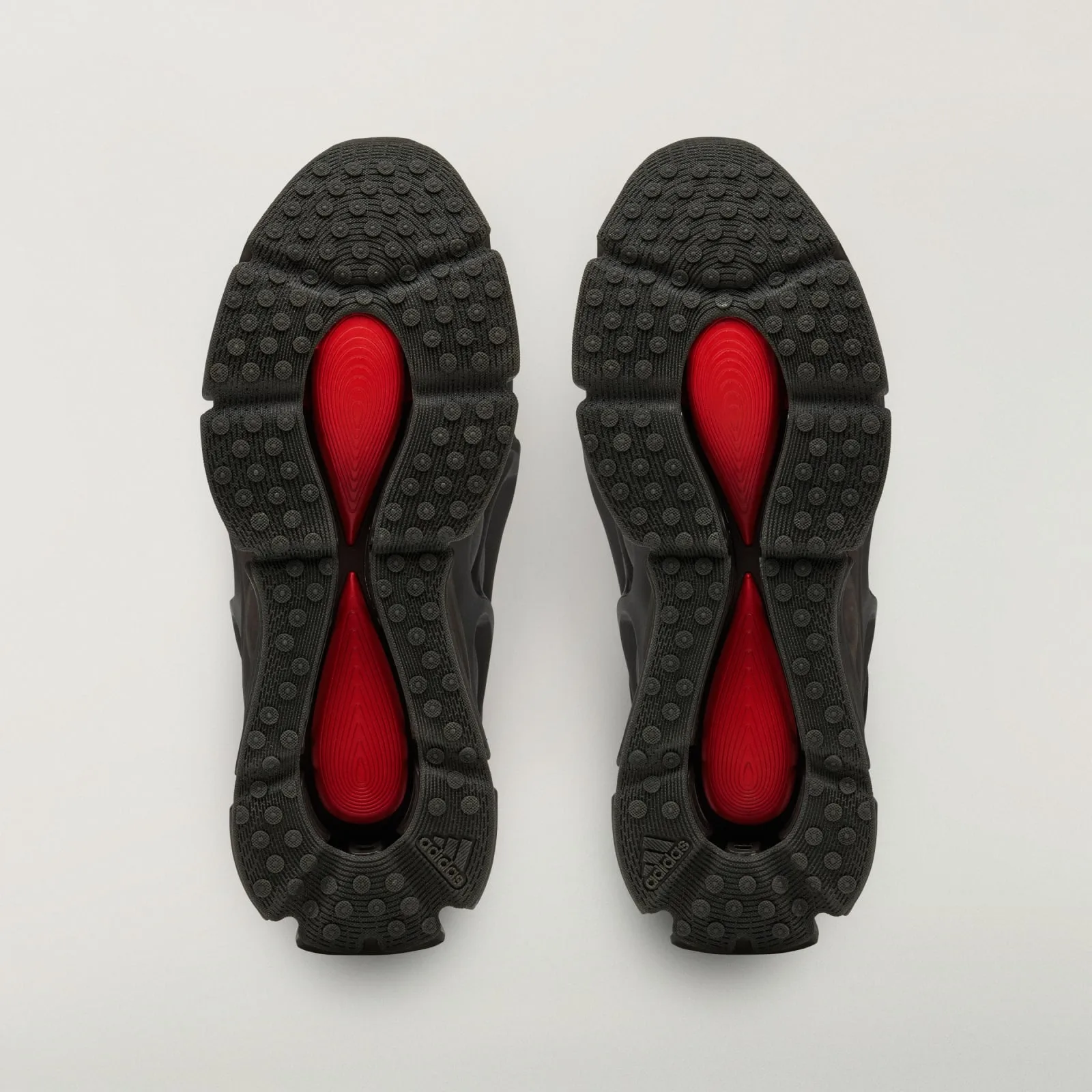 outsole view of pair, black nubbed tread with red teardrop inserts, adidas text, Wolf