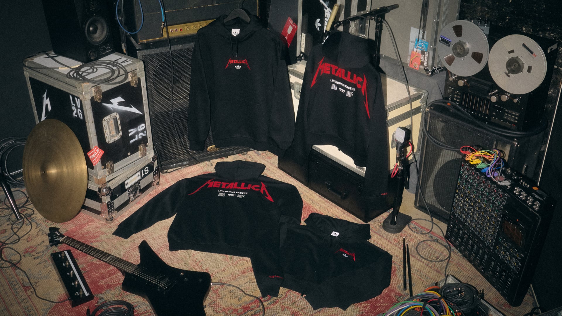 black hoodies with red Metallica logo, 'Life Burns Faster' back print, guitar nearby, Life Burns Faster