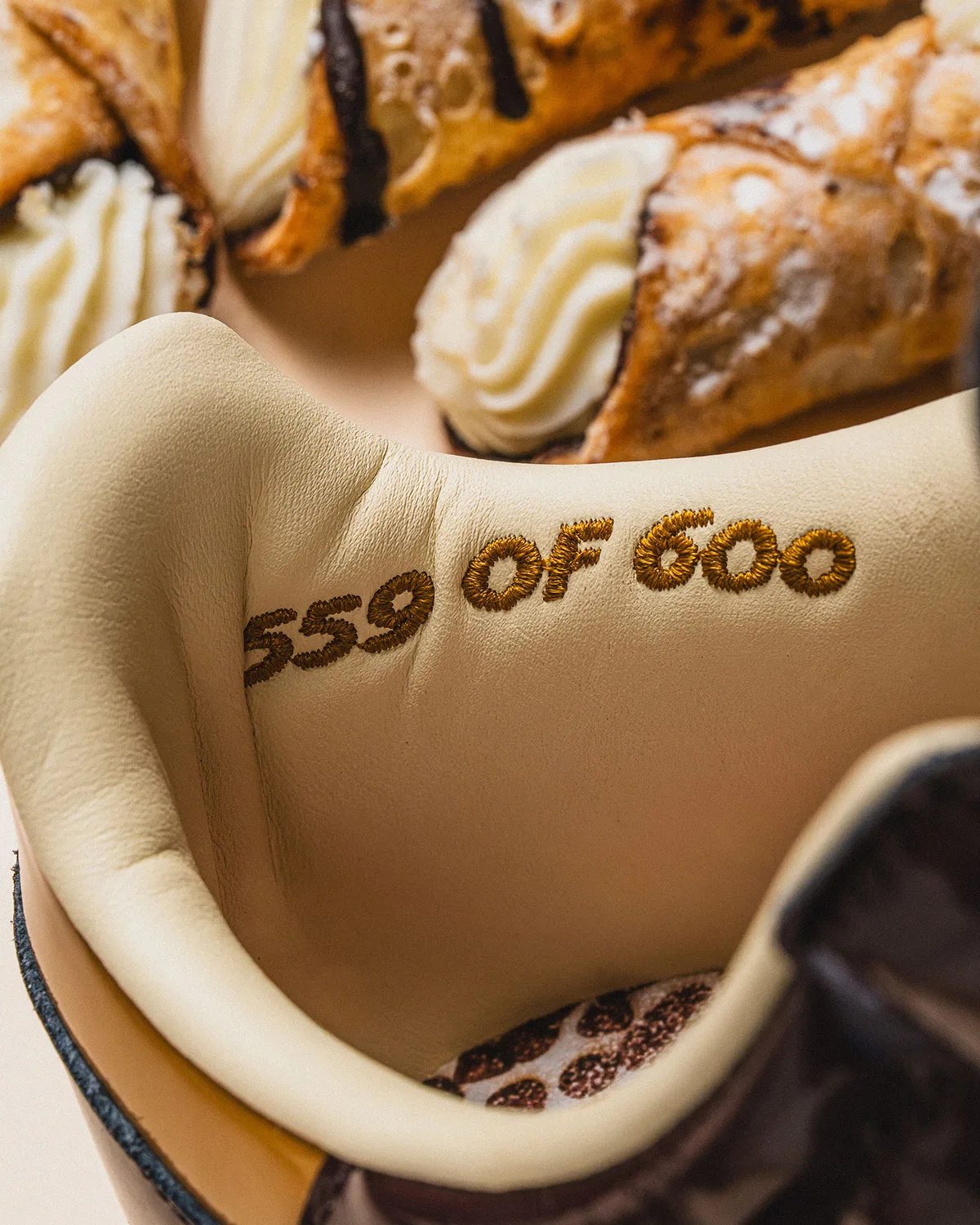 heel lining detail embroidered "559 of 600" in gold thread, cannoli pastries nearby, Cannoli