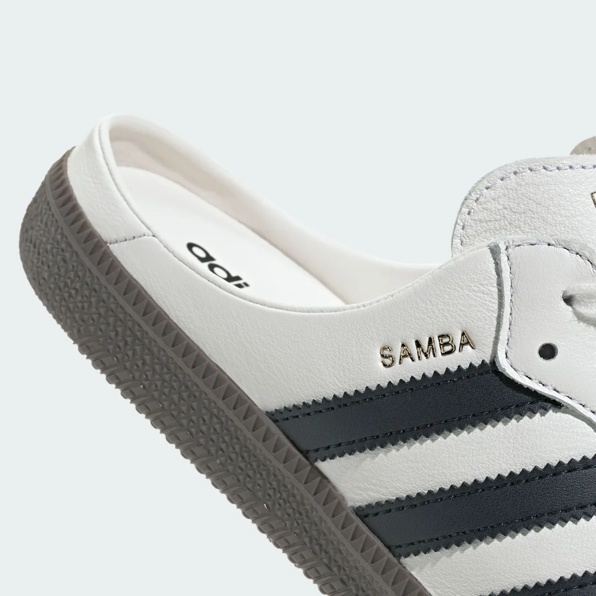 close-up detail of gold Samba text above black stripes near heel, adidas Samba Mule