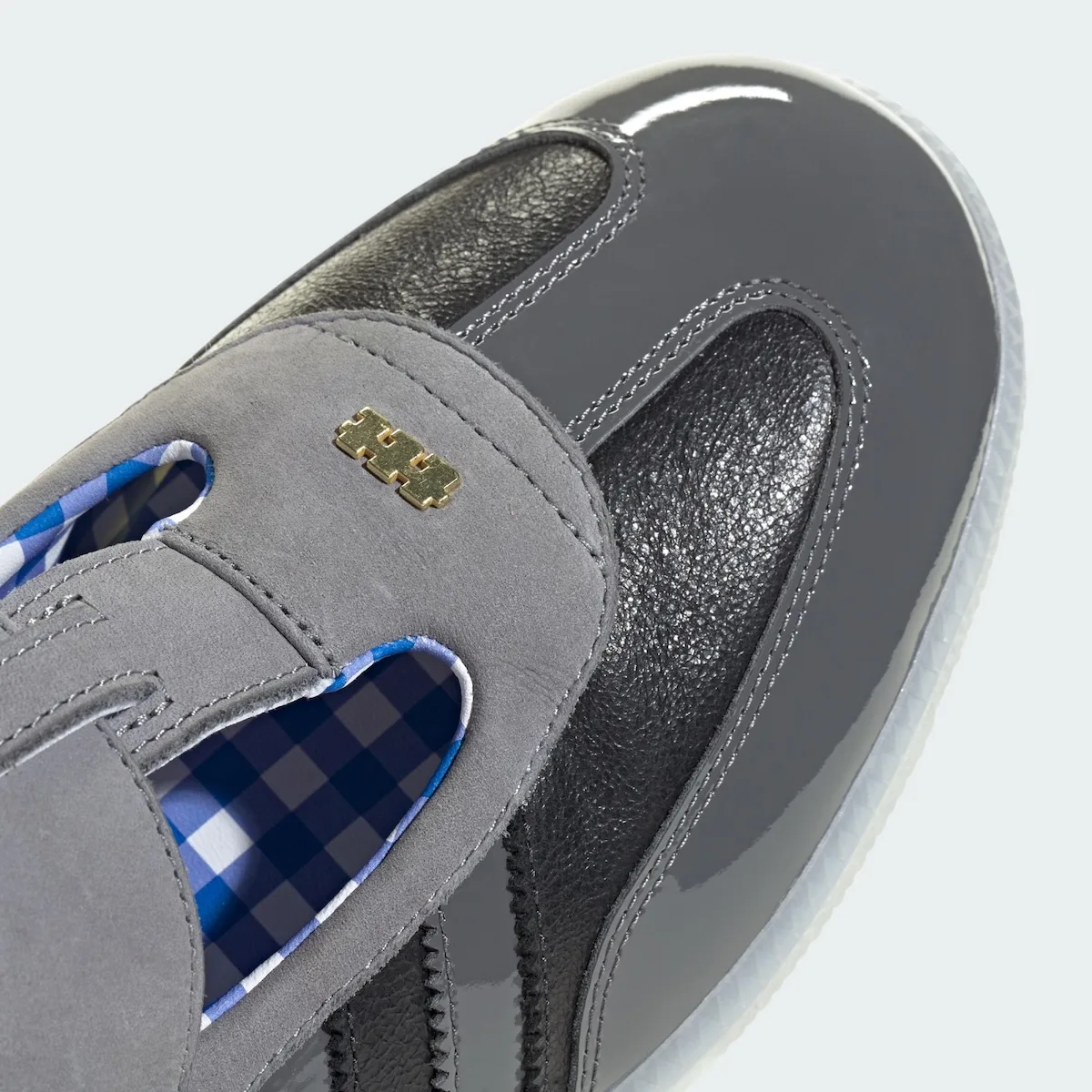 close-up of toe, grey suede strap with gold hardware stud on black patent, x TTT MSW
