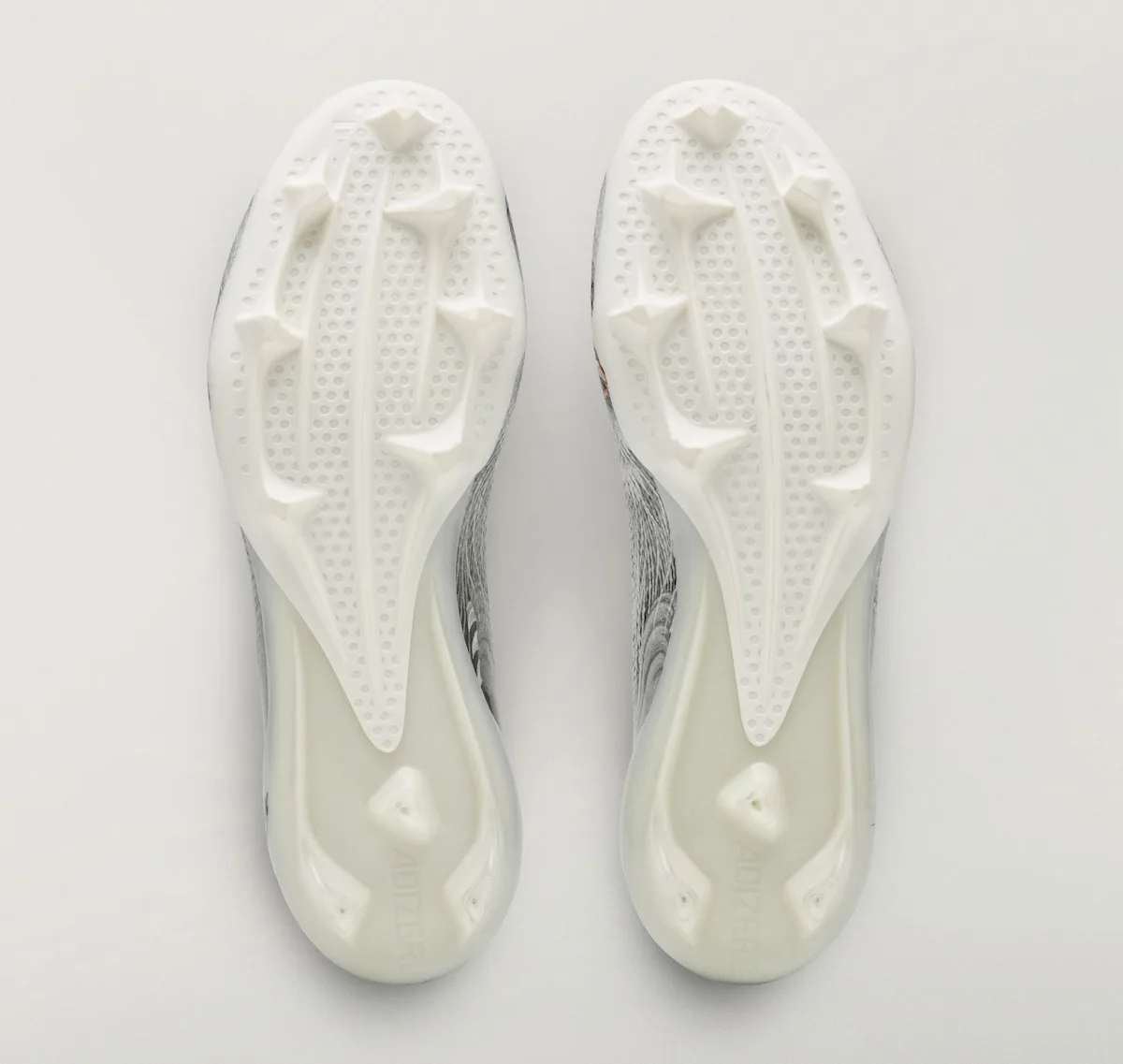 Outsole view of the pair, white studded soles with grey and red uppers visible, Beast