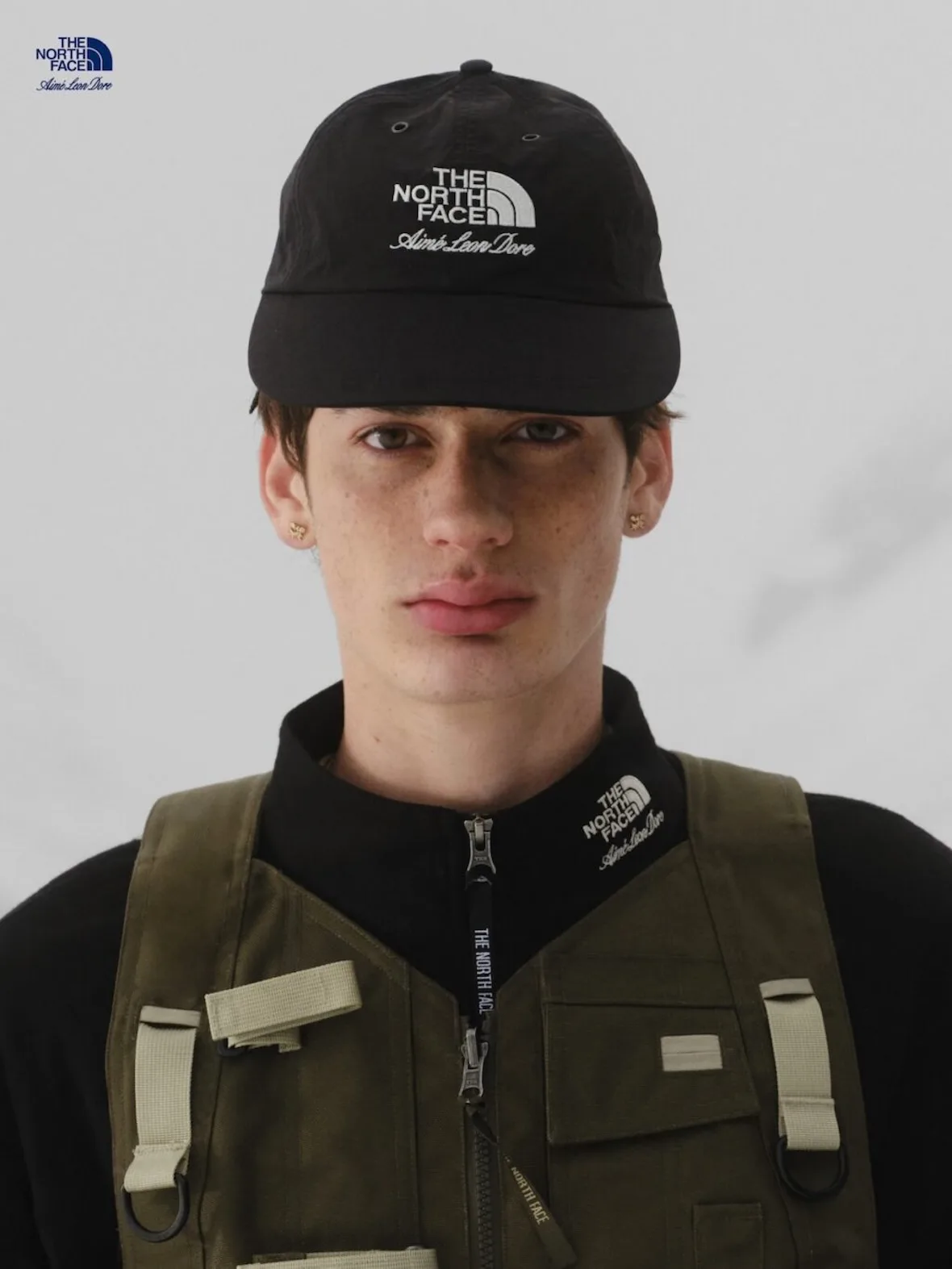 portrait, black logo cap and olive utility vest over black base layer, Fall/Winter 2026 Collection