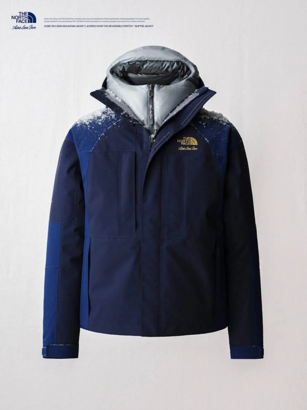 flat-lay, navy gore-tex jacket with grey puffer hood beneath, gold logo, Fall/Winter 2026 Collection