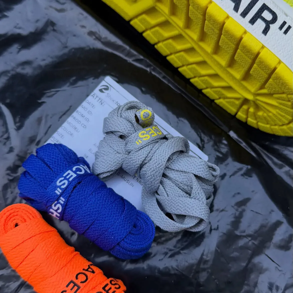 detail shot of loose grey, blue and orange replacement laces beside yellow outsole, Black/Lightning