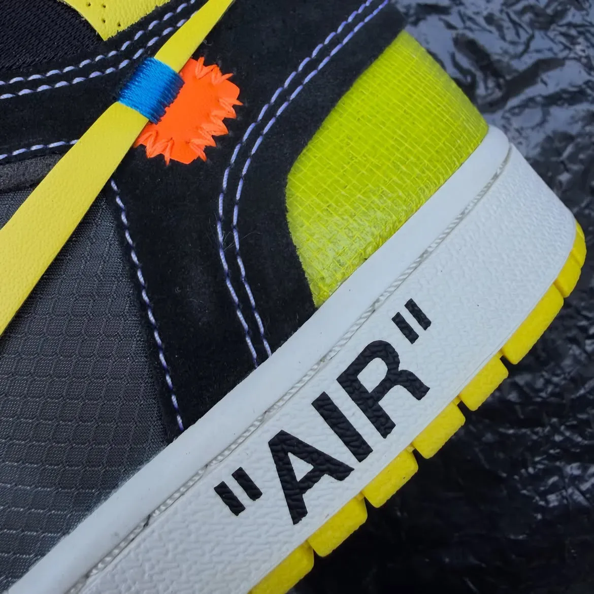 close-up of orange zip-tie tag and quoted "AIR" text on white midsole, Black/Lightning