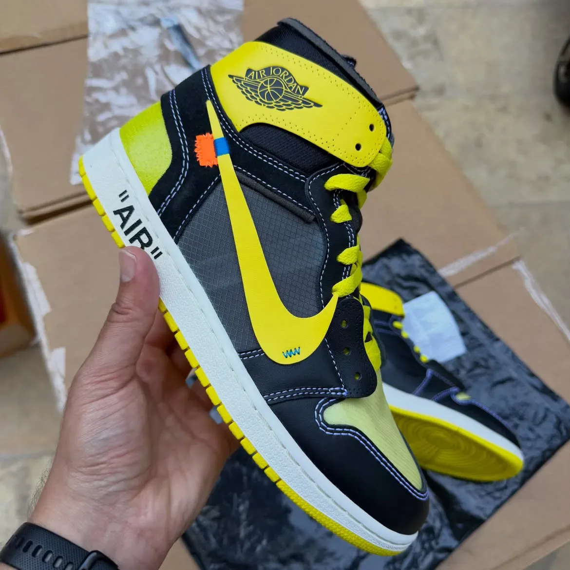 in-hand lateral view of black and yellow high-top with orange zip-tie tag, Black/Lightning