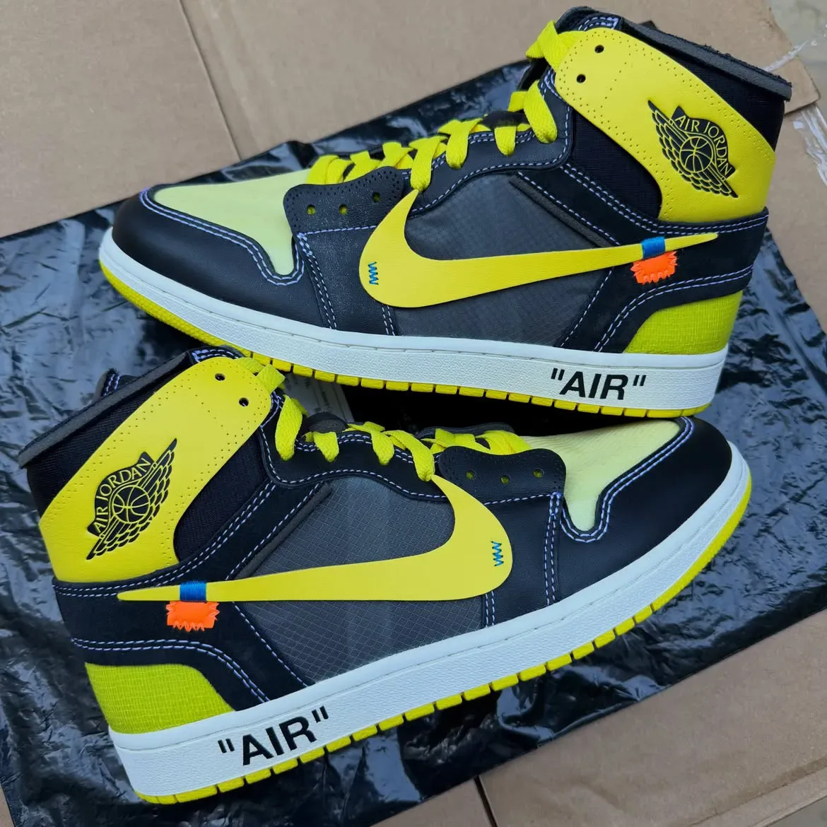 pair lateral view showing yellow Jordan Wings logo and quoted "AIR" midsole text, Black/Lightning