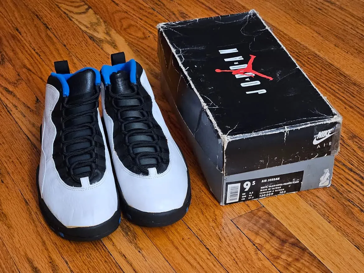 pair on wood floor beside Jordan box, black laces and blue tongue lining, Knicks