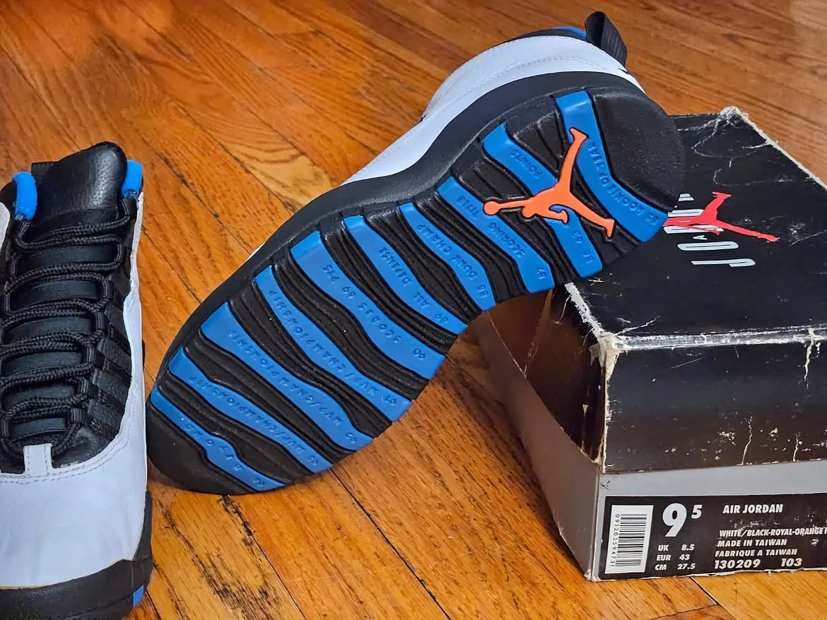 outsole close-up propped on box, orange Jumpman and blue/black tread stripes, Knicks