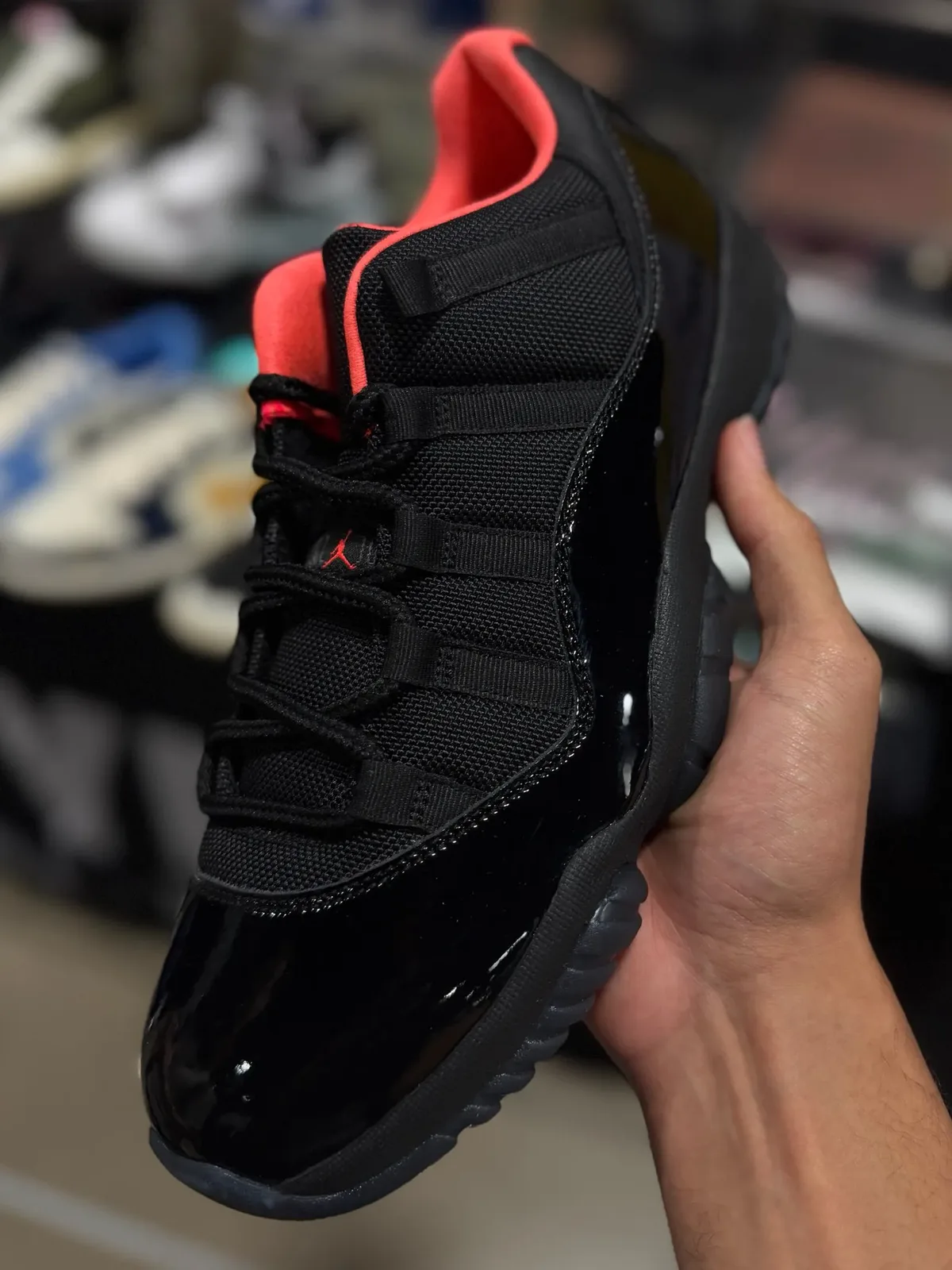 held in hand, black mesh and patent upper with coral collar and red Jumpman tongue tag, Black Infrared