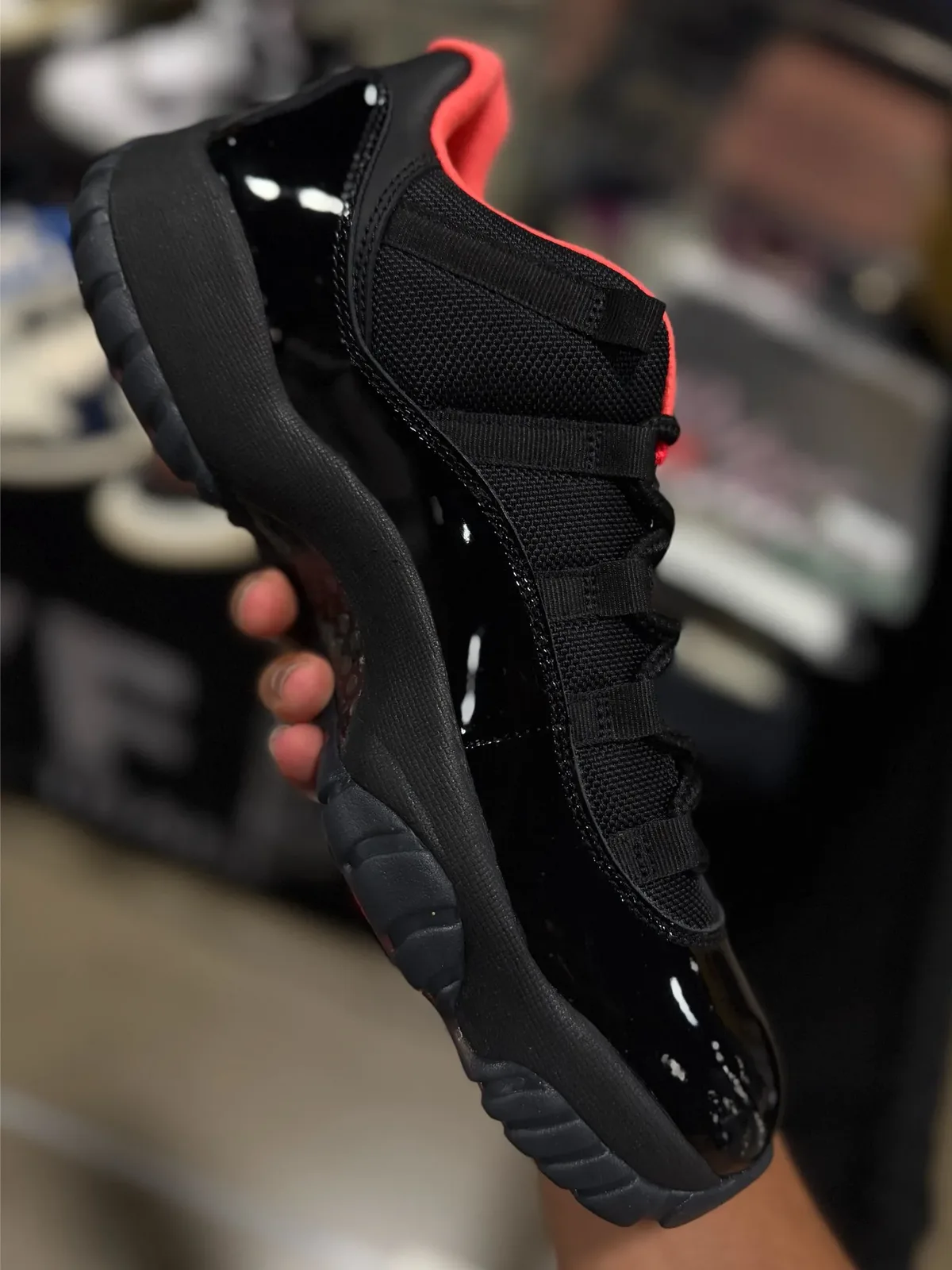 held in hand, angled heel view showing black patent heel and dark ridged outsole, Black Infrared