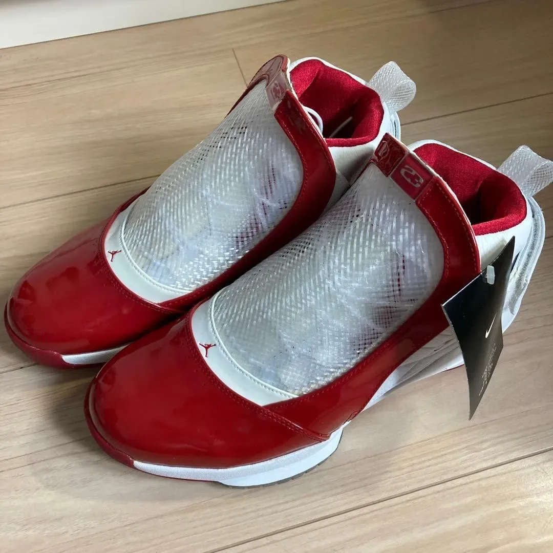 front-angled pair, glossy red patent toes, red Jumpman logos, wood floor, Midwest
