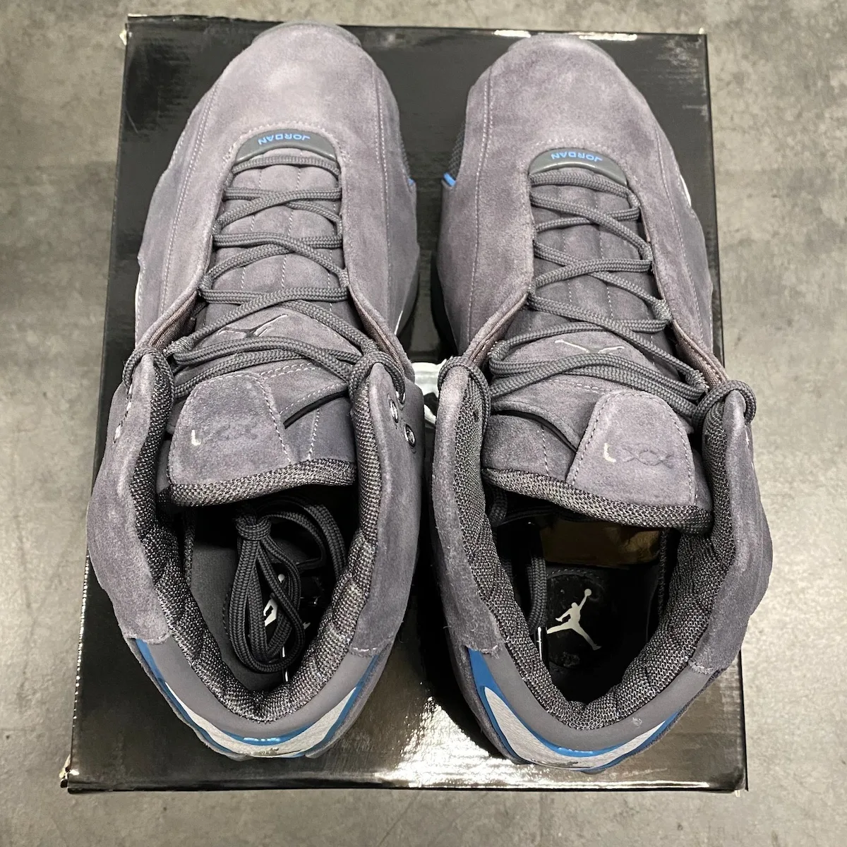 top-down pair on box, toe boxes together, JORDAN tongue tabs, blue lining visible, Light Graphite