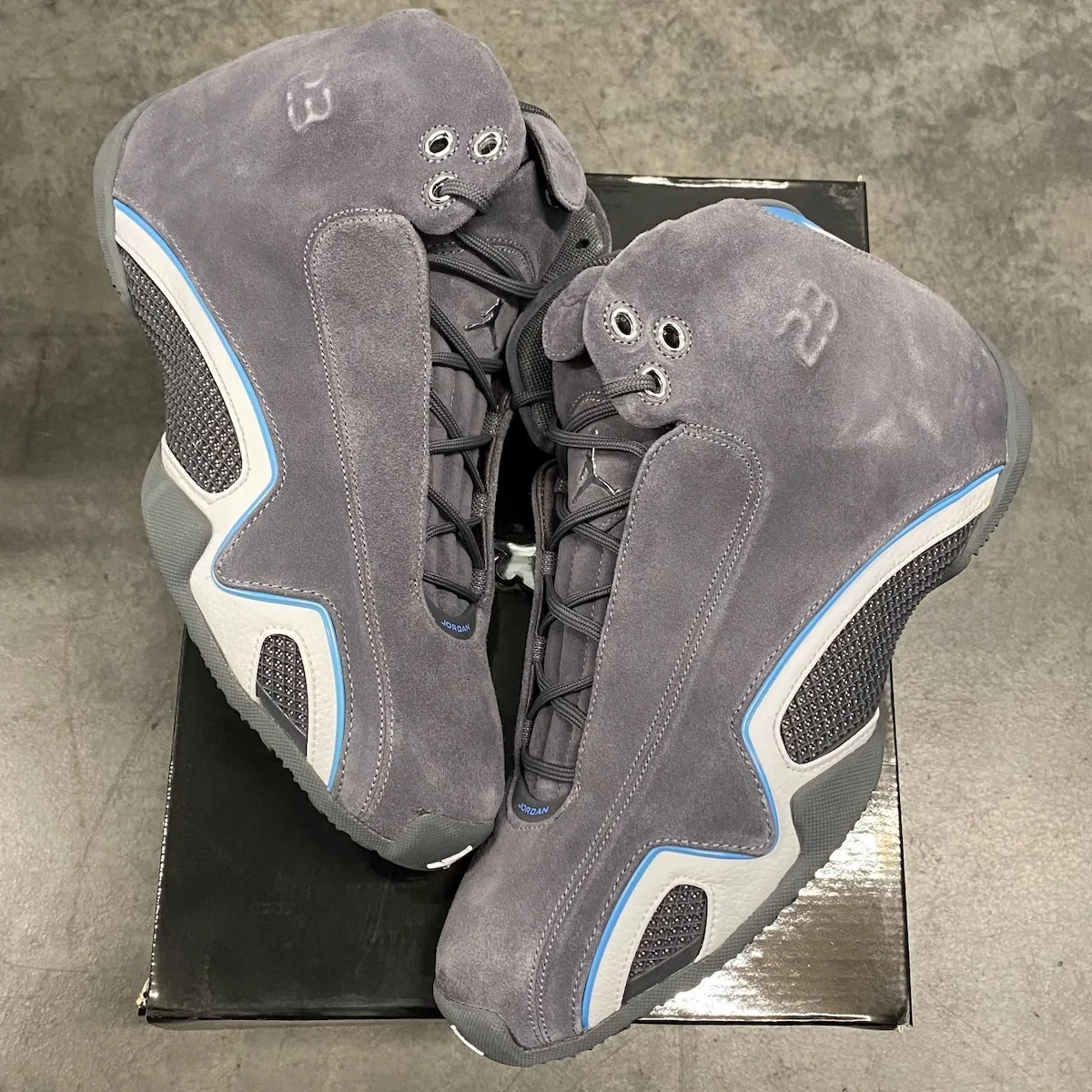 top-down pair on shoebox, grey suede, embossed numerals on heel, concrete floor, Light Graphite