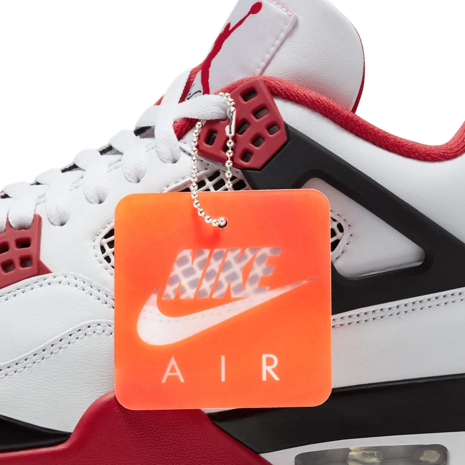 lace close-up with orange 'NIKE AIR' hangtag clipped to a red eyelet, Fire Red